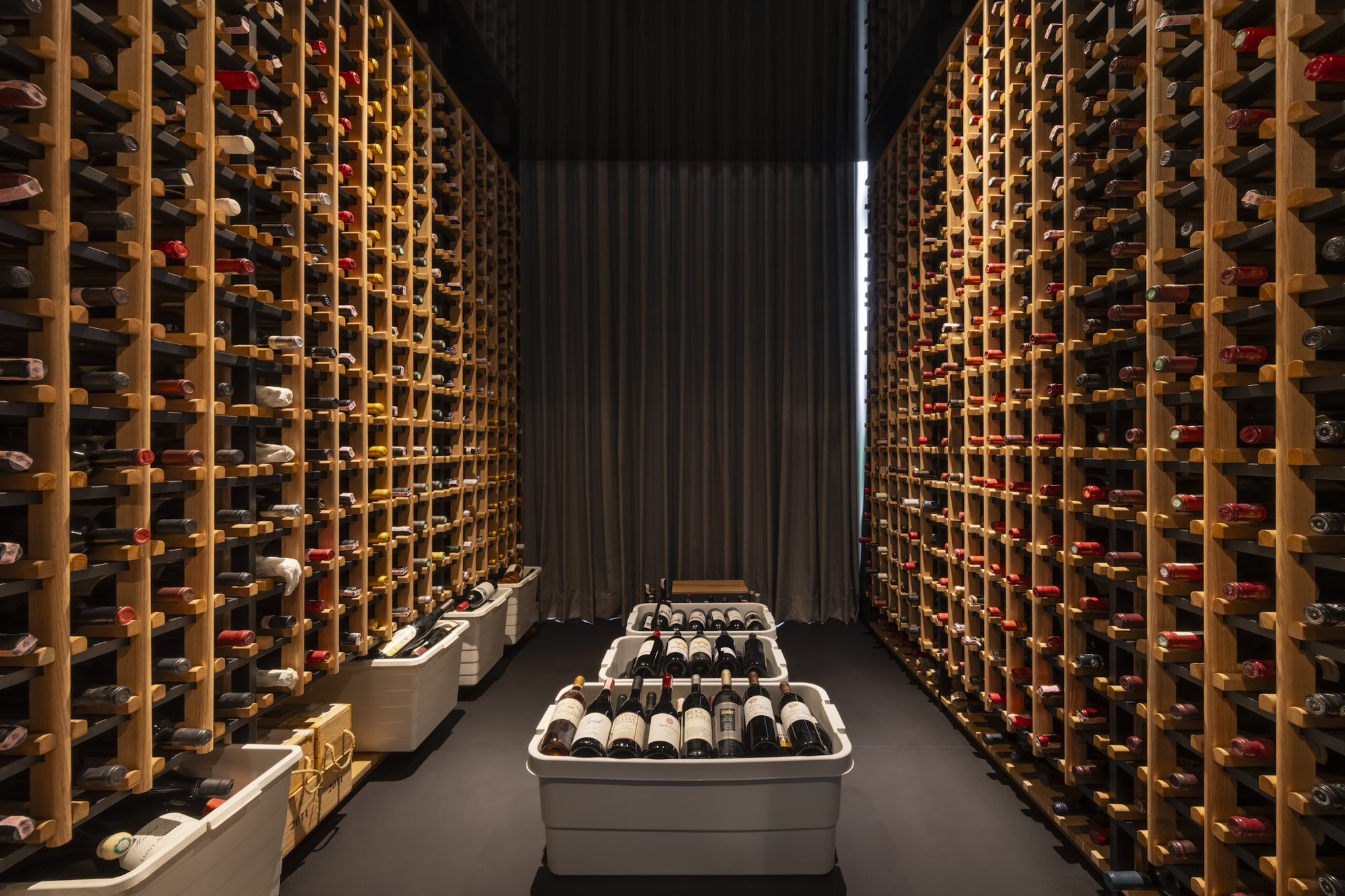 Wine cellar with floor-to-ceiling timber racking illuminated by vertical strip lighting