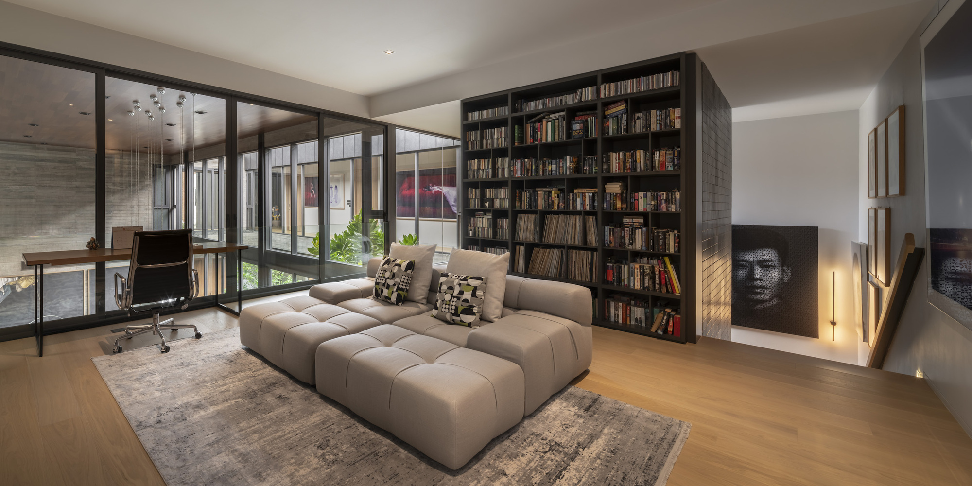 Living room with floor-to-ceiling bookshelf and glazed wall opening to an interior courtyard