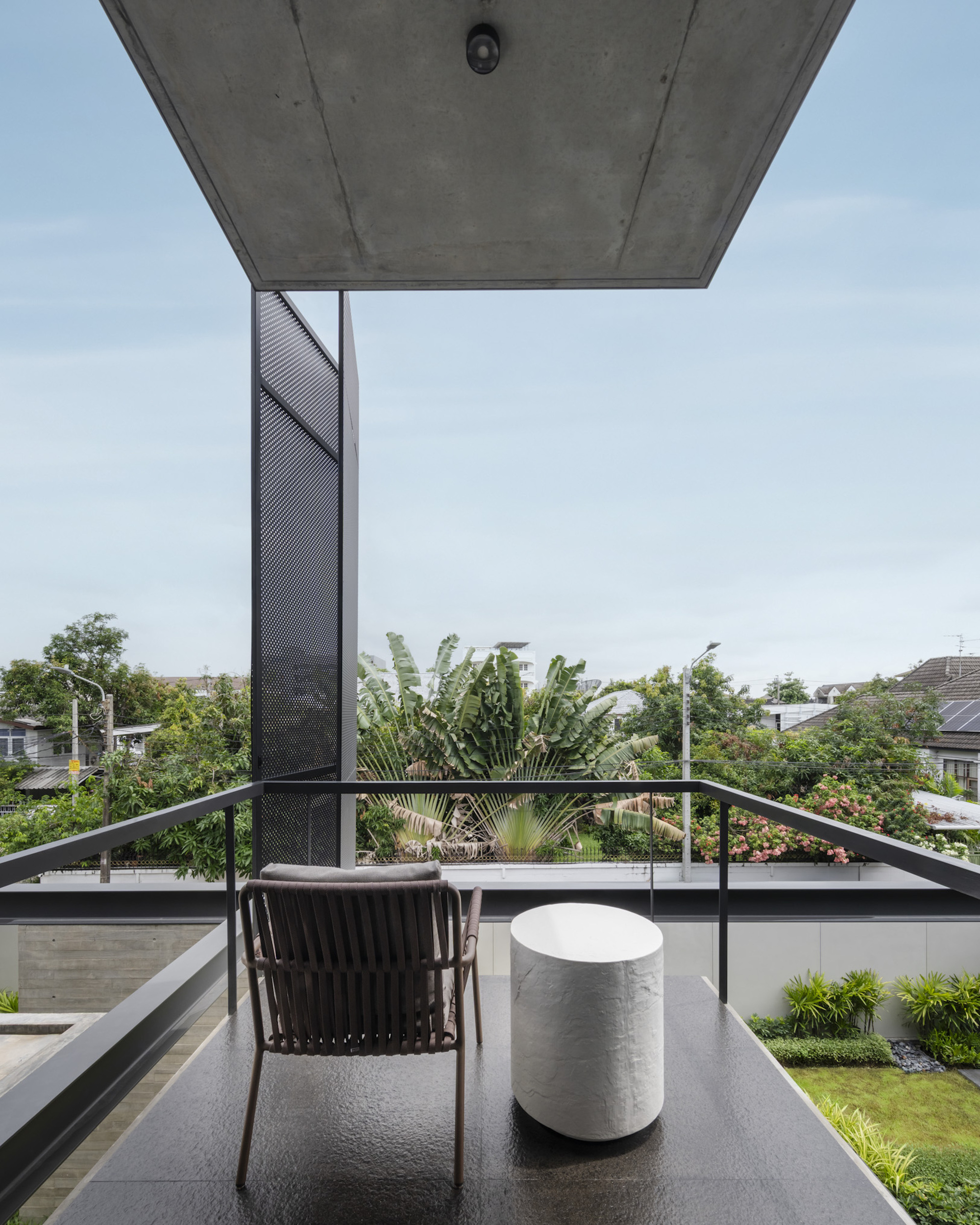 Rooftop terrace with metal railing and perforated screen column overlooking residential neighborhood