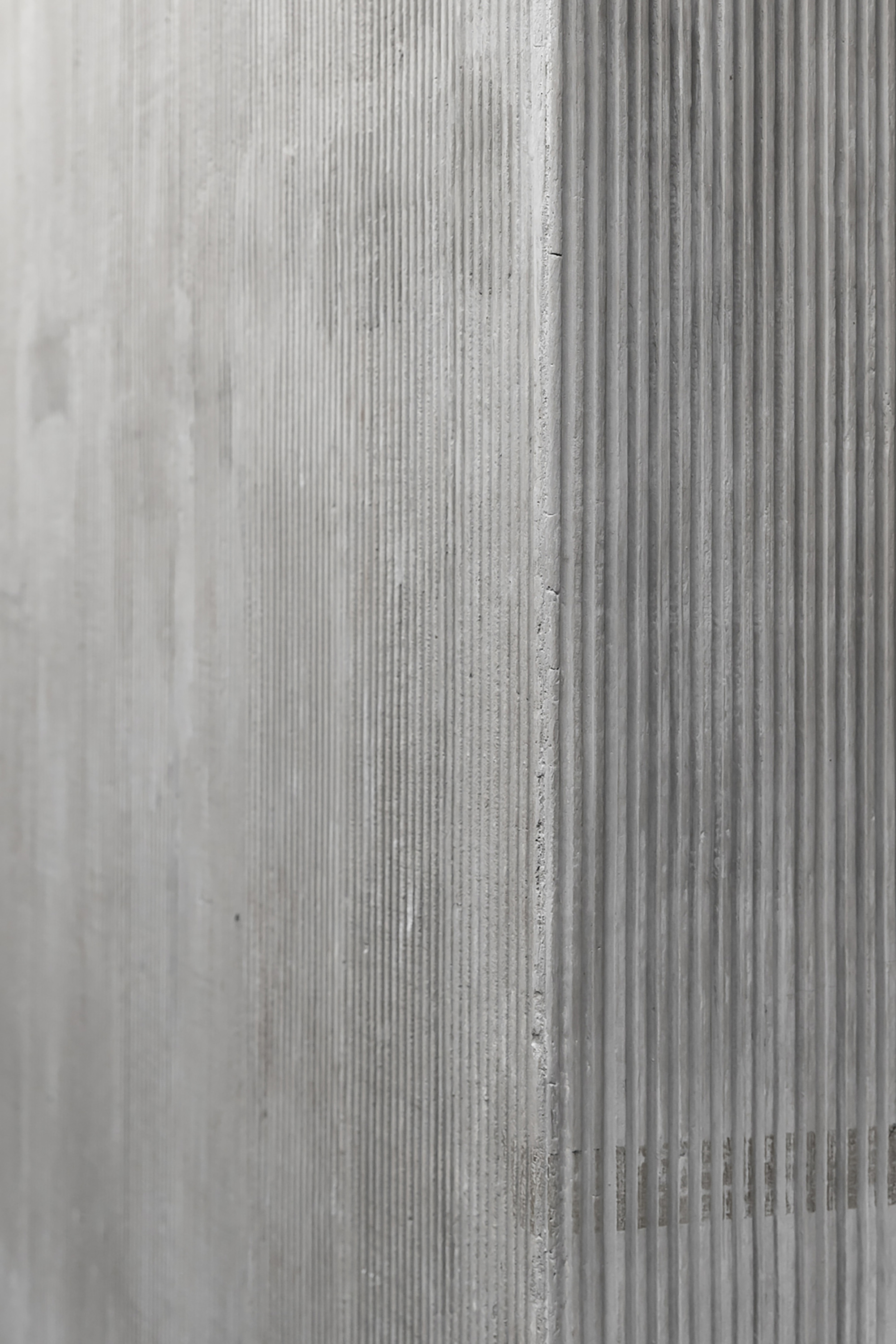 Close-up of cast concrete wall surface showing vertical ribbed formwork texture and seam joint