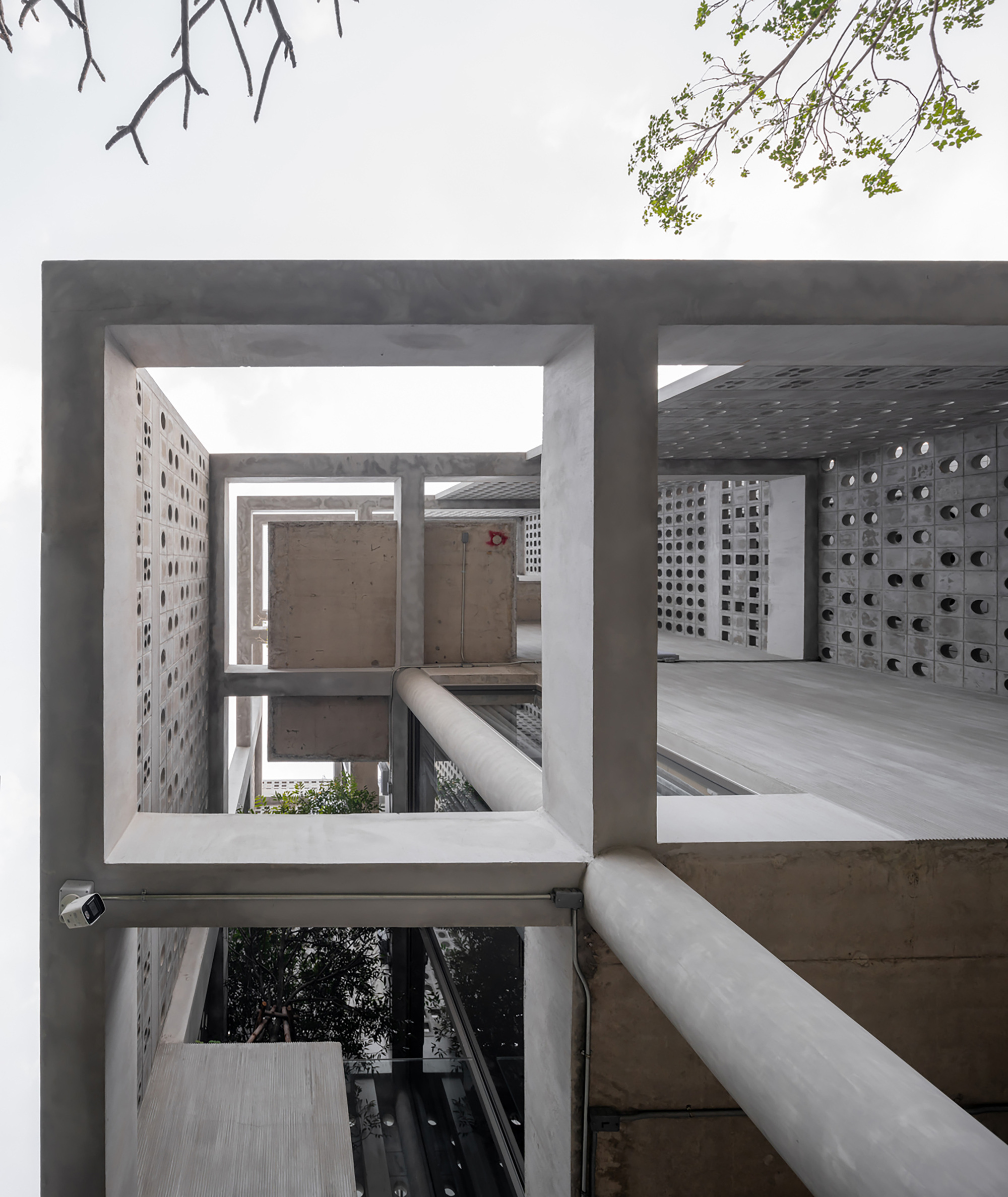 View through concrete framed openings showing perforated block walls and corridors with planted beds below
