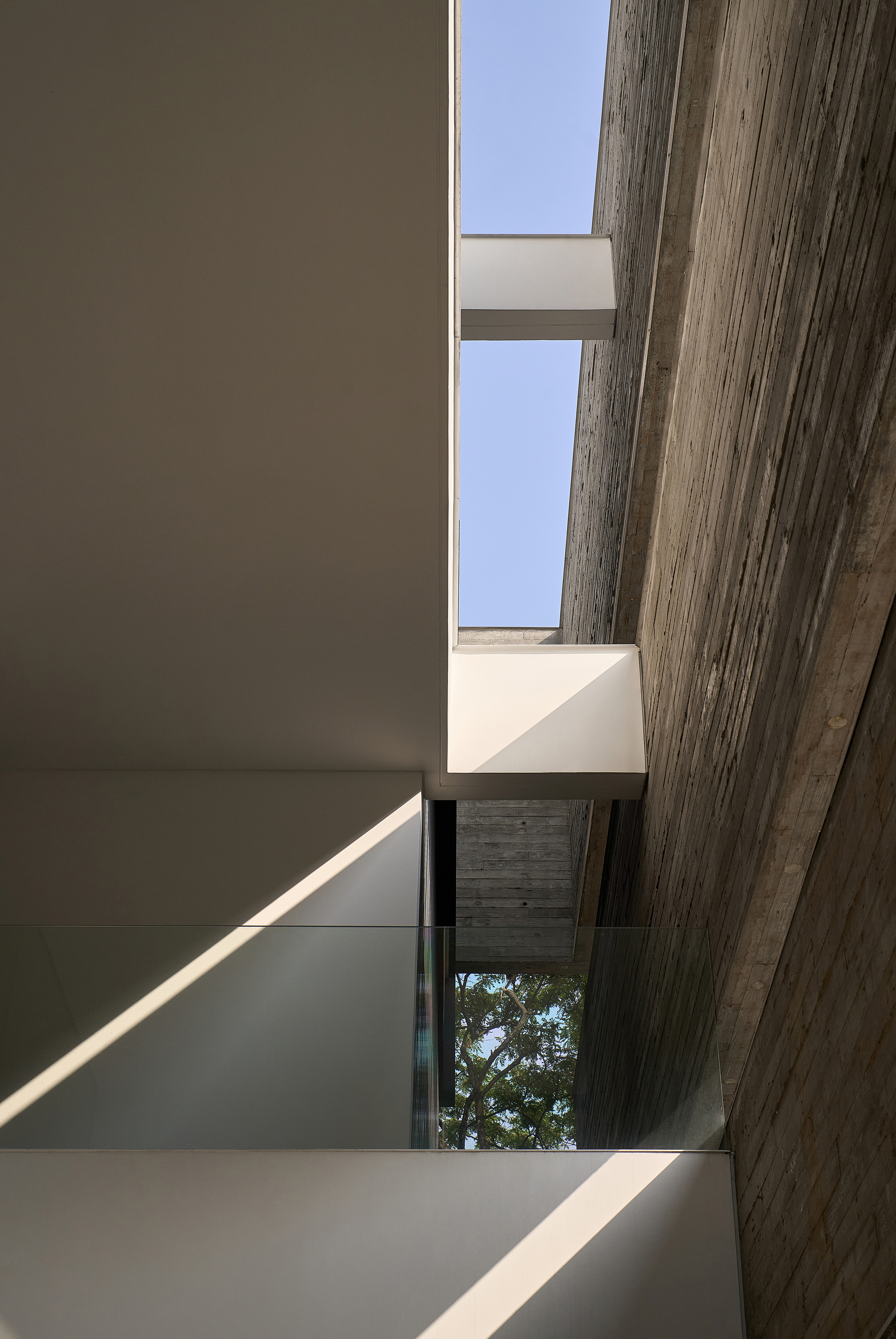 Interior stairwell skylight framed by board-formed concrete beams and white plaster walls