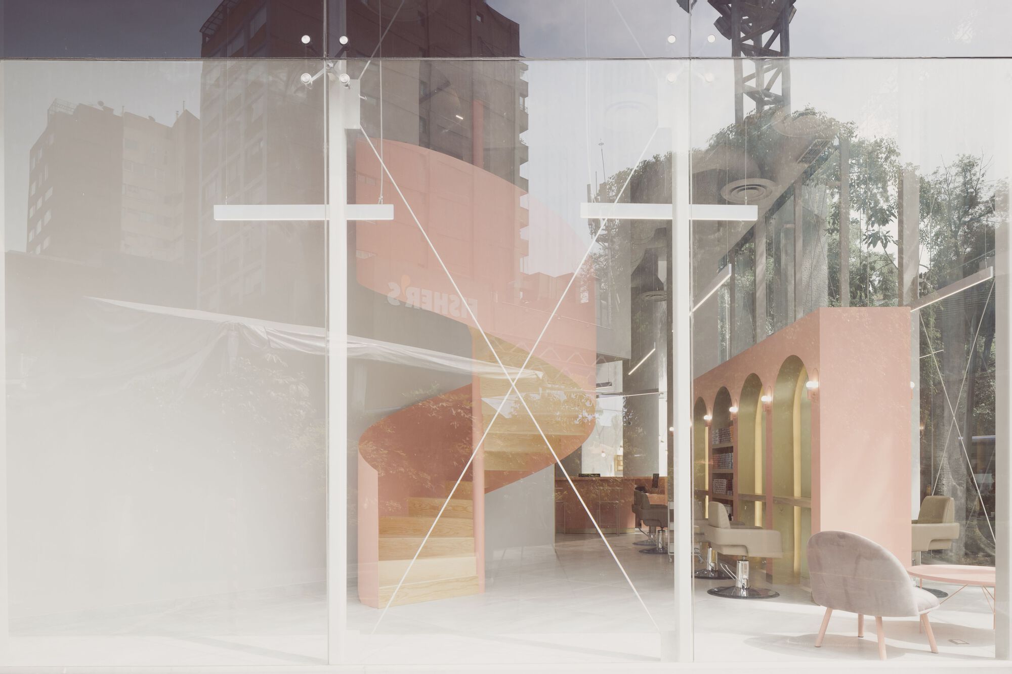 View through frosted glass panels showing the pink spiral stair and interior salon space beyond