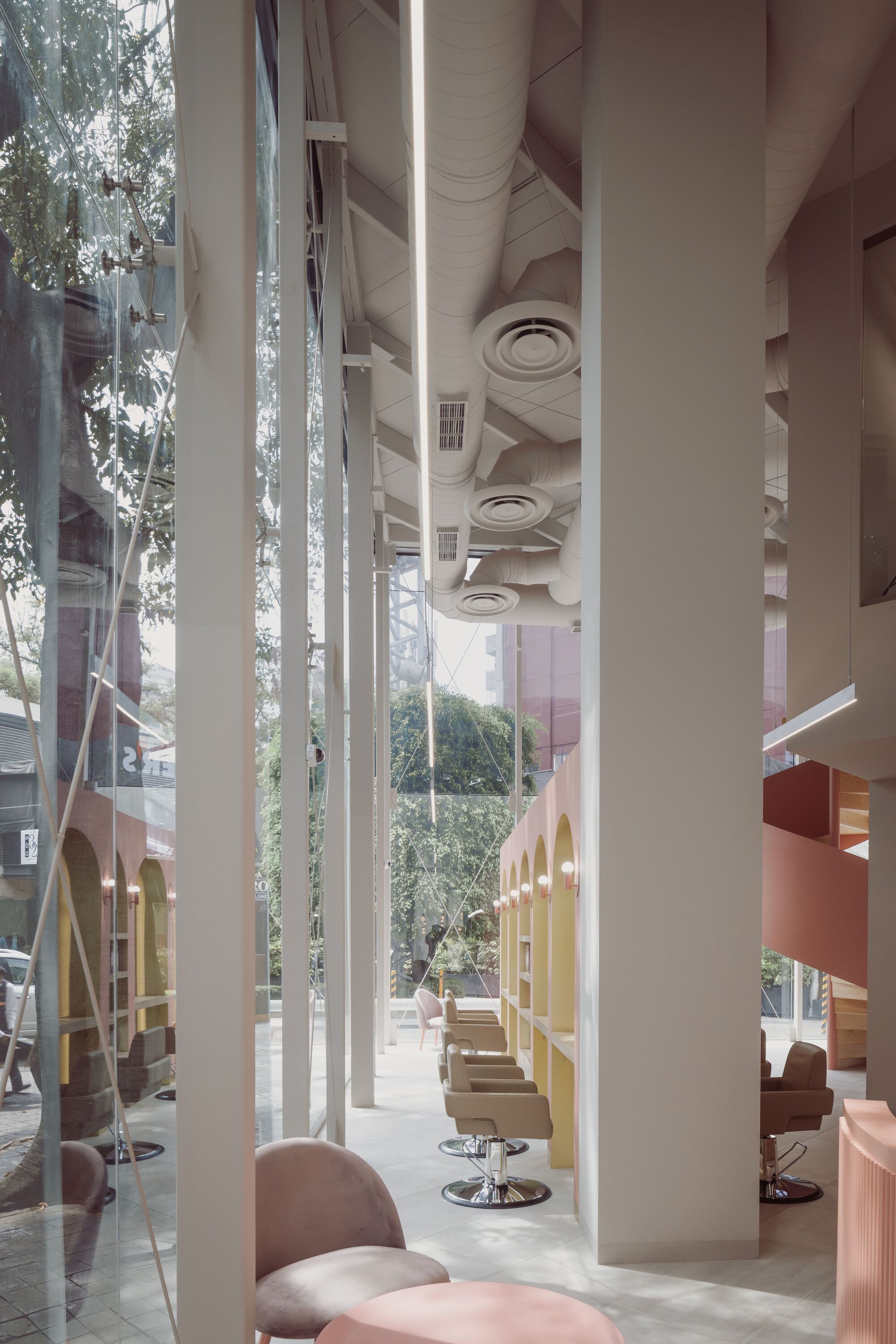 Double-height interior with white circular columns, sculpted ceiling coffers, and natural light from the glazed facade