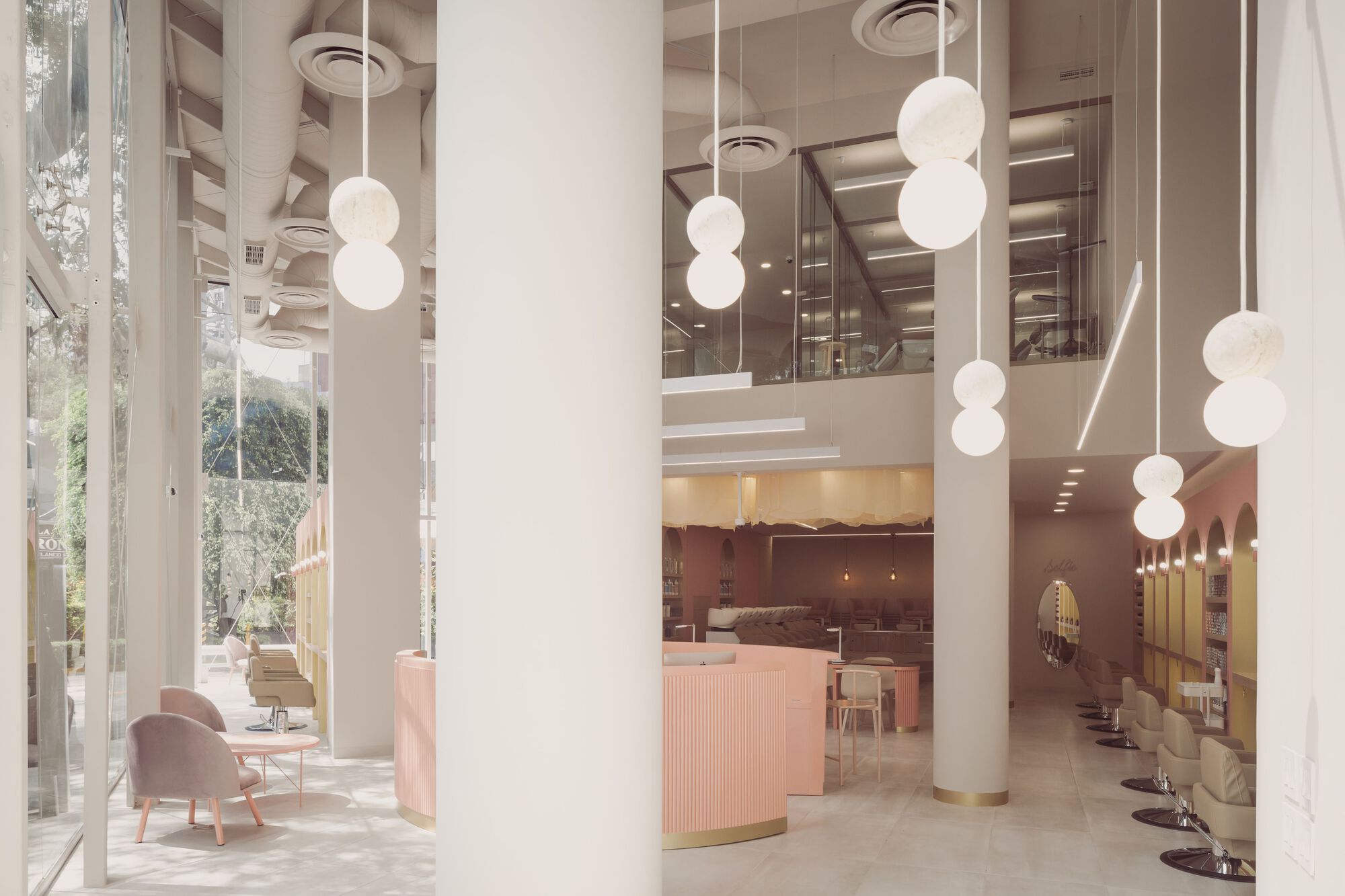 Interior reception area with spherical pendant lights, white columns, and mezzanine levels visible above