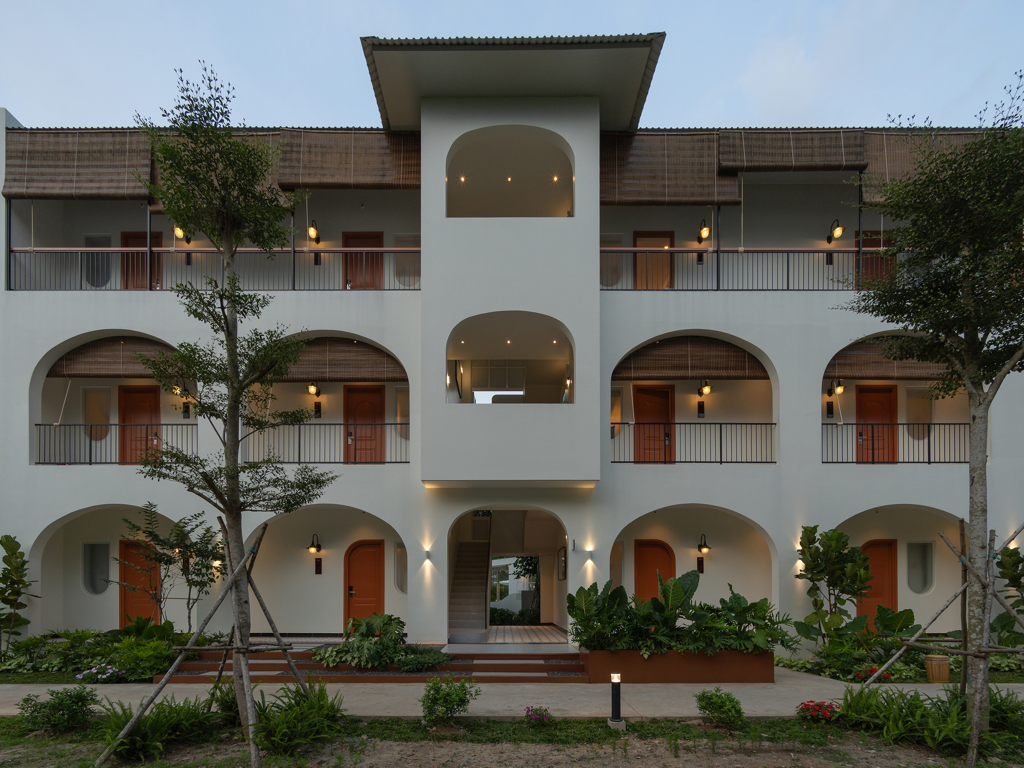 Symmetrical three-story facade with arched openings and central entrance pavilion at twilight
