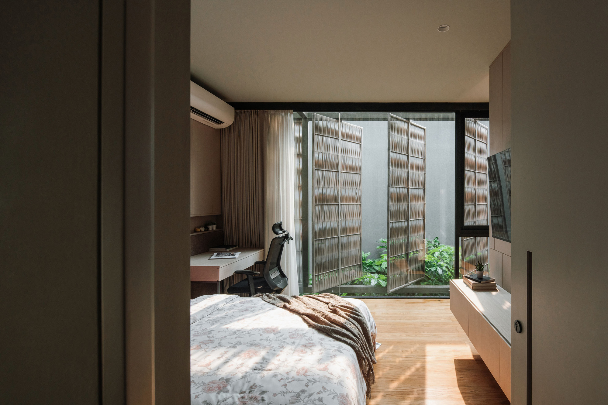 Bedroom view through open sliding doors to a courtyard with lattice screens and small planted garden
