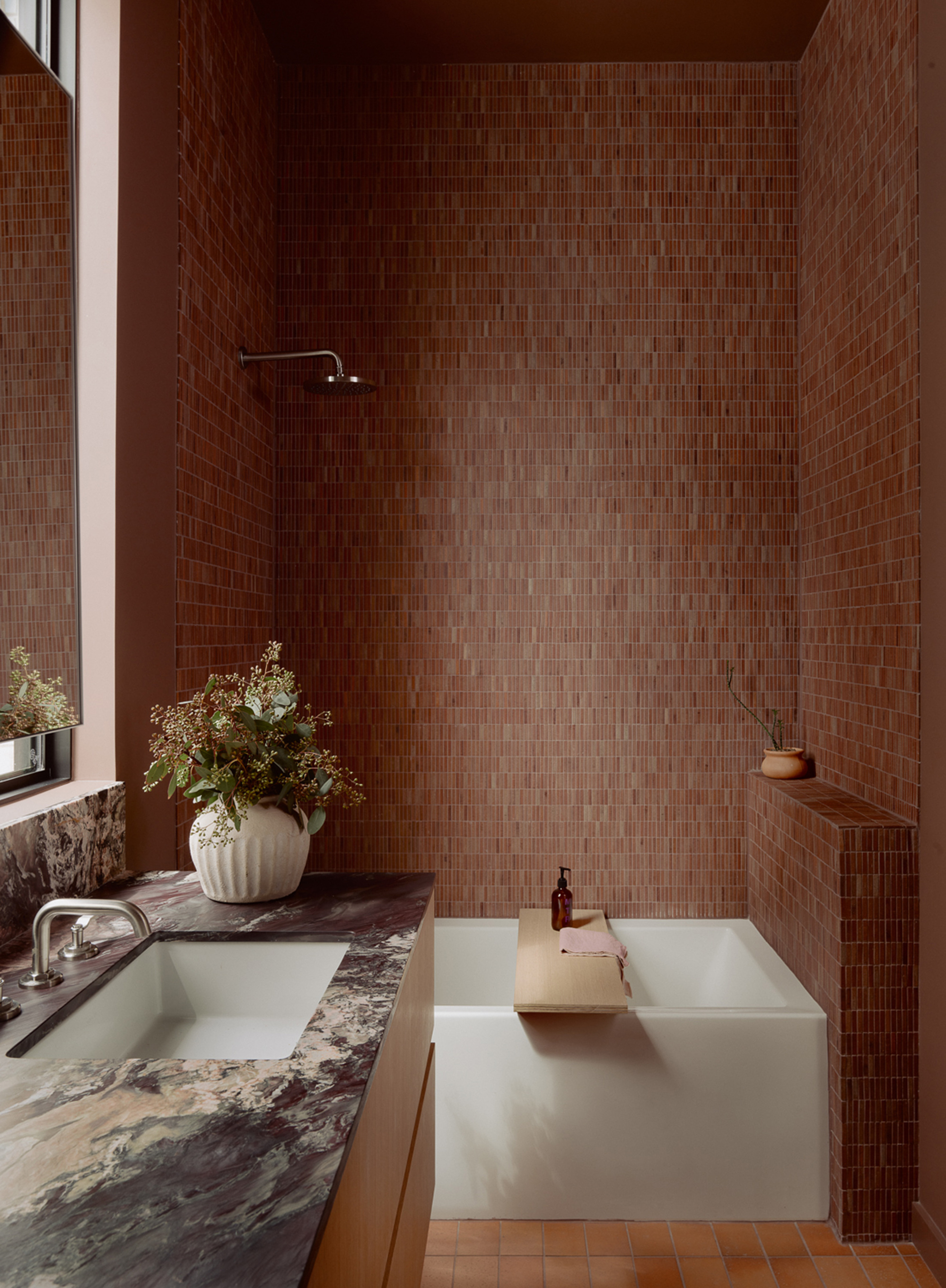 Bath alcove clad entirely in small brown mosaic tiles with freestanding tub and overhead shower