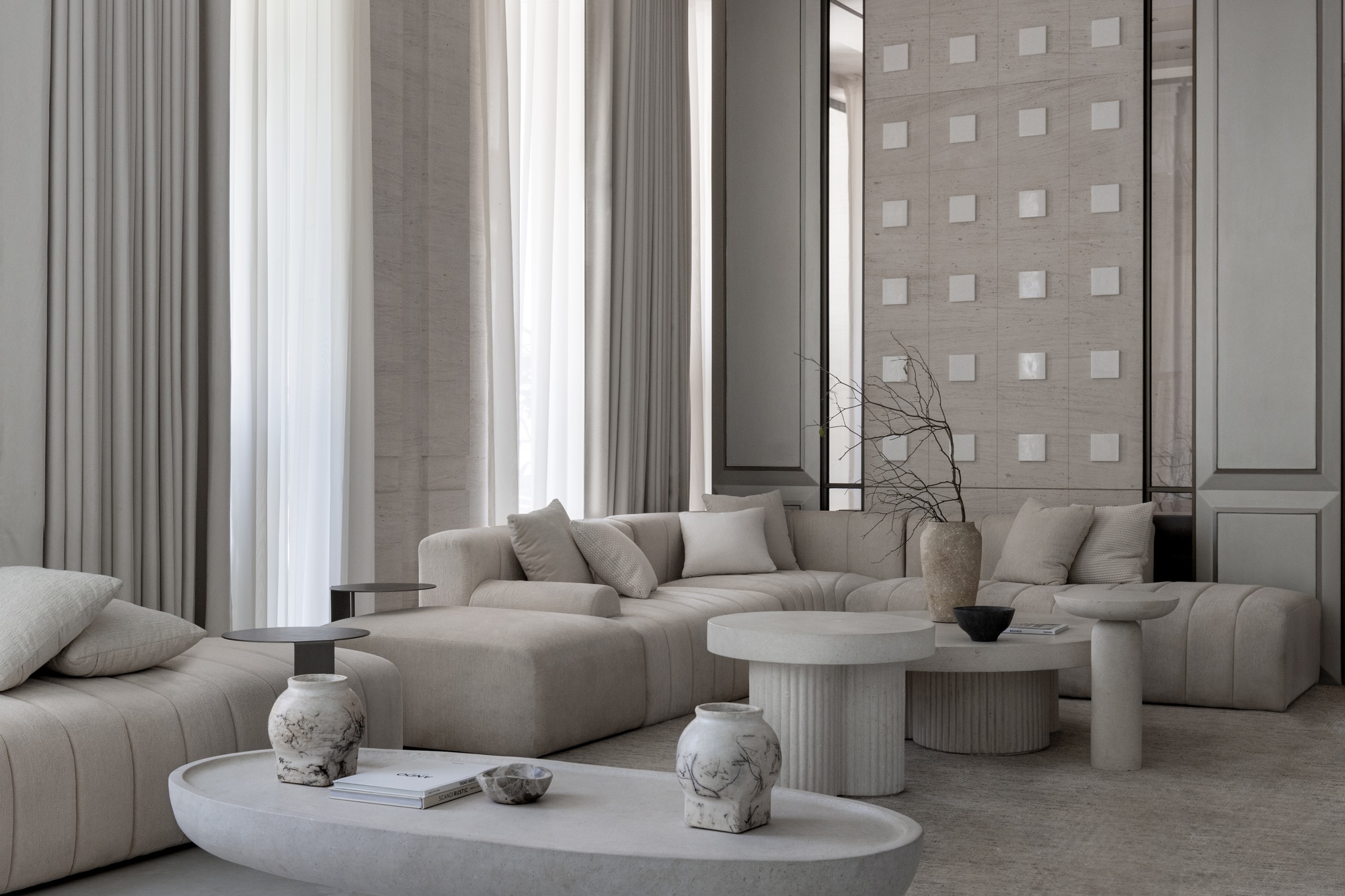 Double-height living room with floor-to-ceiling curtains and grey upholstered seating around circular tables