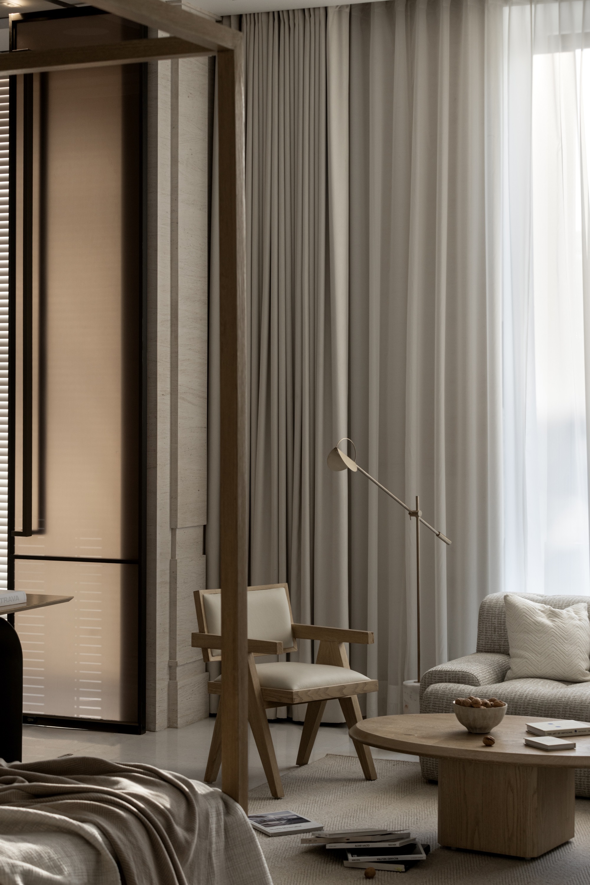 Living area with floor-to-ceiling curtains, timber chairs, and a brass articulating floor lamp