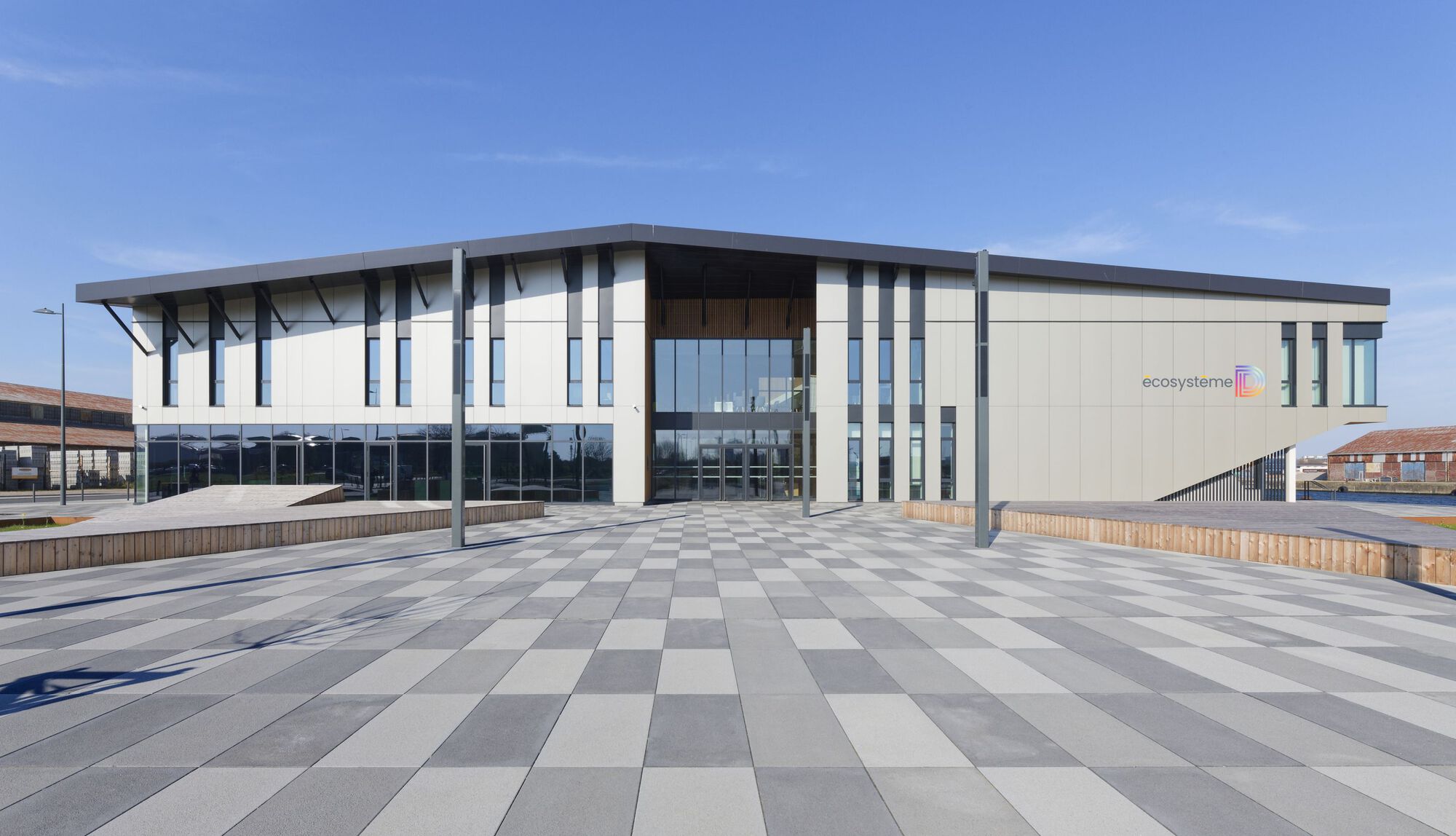 Main entrance plaza with chequered paving and cantilevered canopy on a clear day