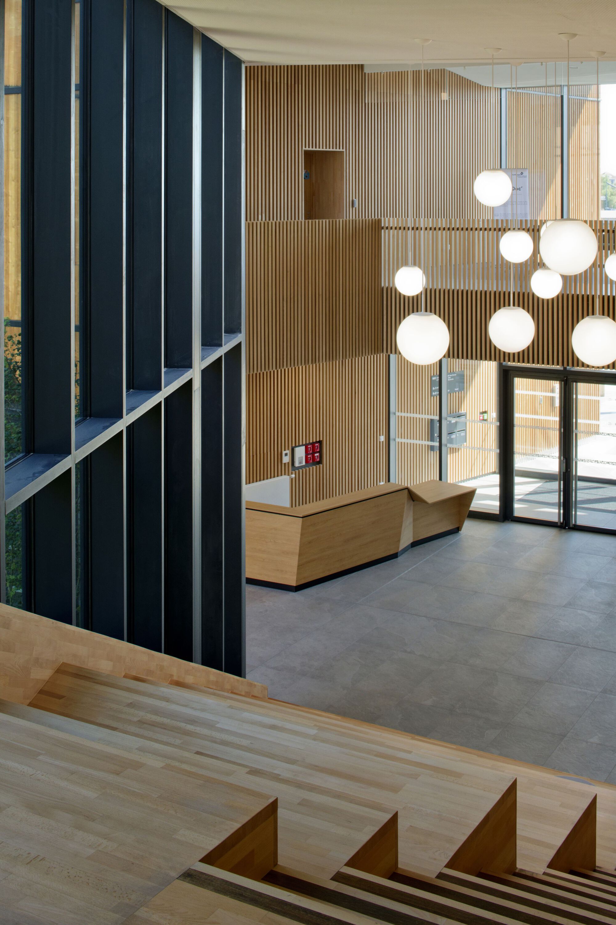 Double-height lobby with sphere pendant lights and timber staircase visible in foreground