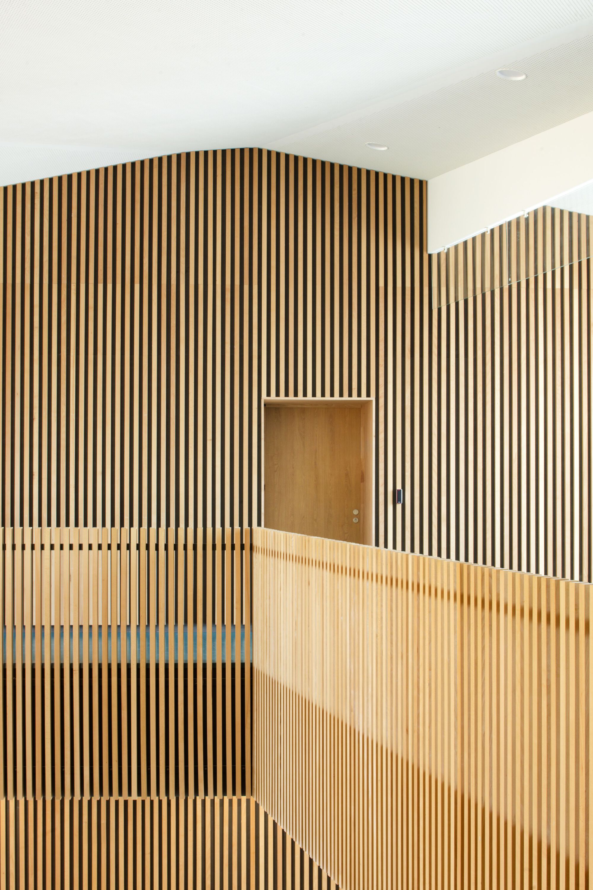 Vertical timber slatted wall with recessed door opening and glazed balustrade below