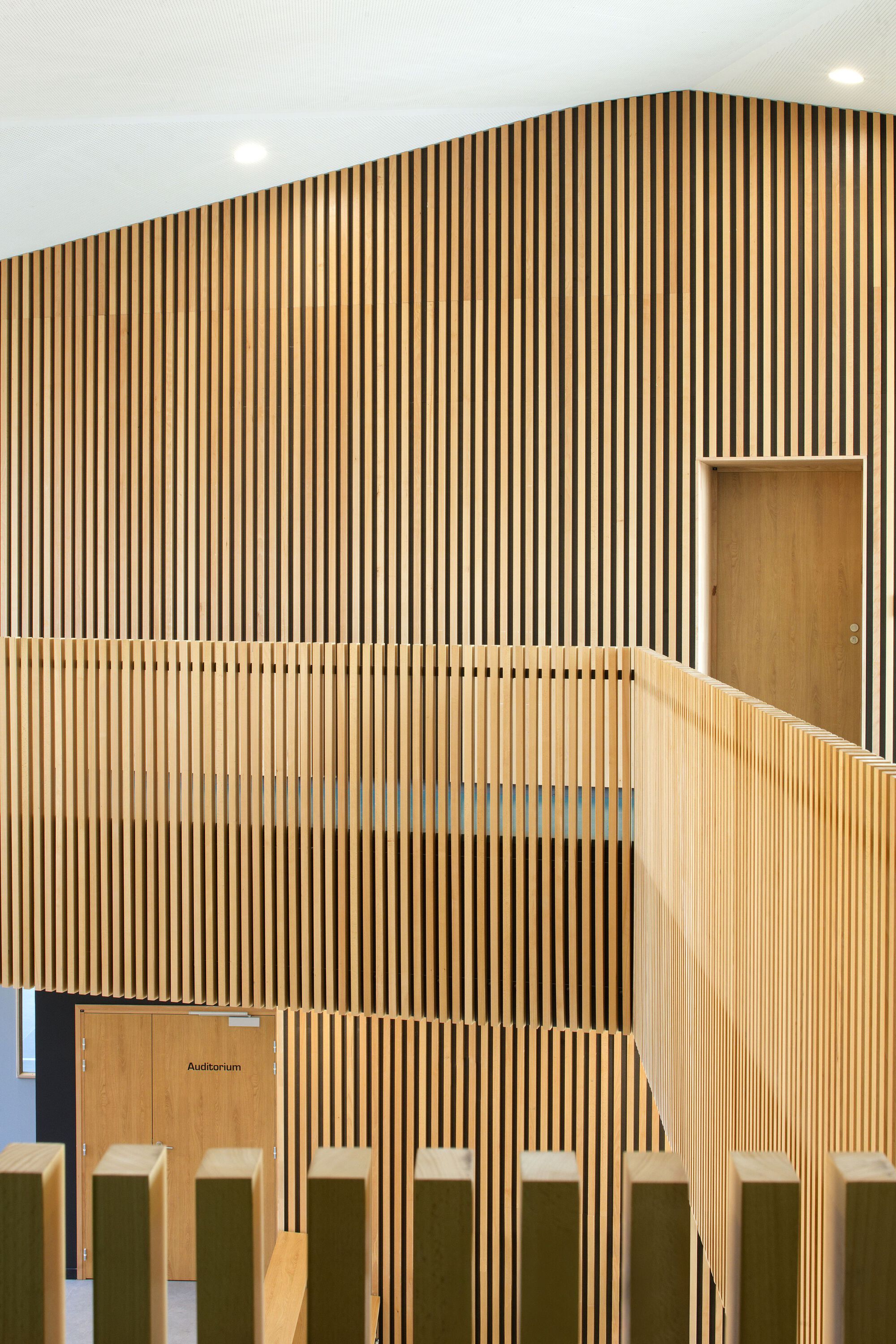 Angled view of timber slat wall showing recessed door and balustrade top rail