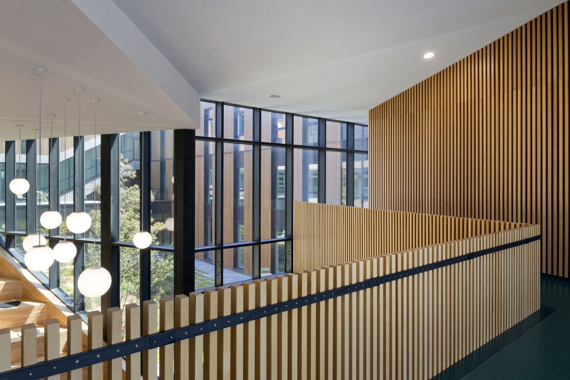 Upper level landing with timber slat wall and black steel handrail overlooking courtyard