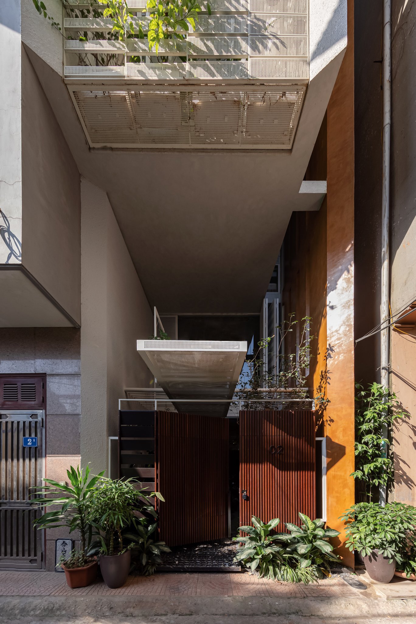 View up through the planted courtyard void showing perforated metal balcony floors and skylight above