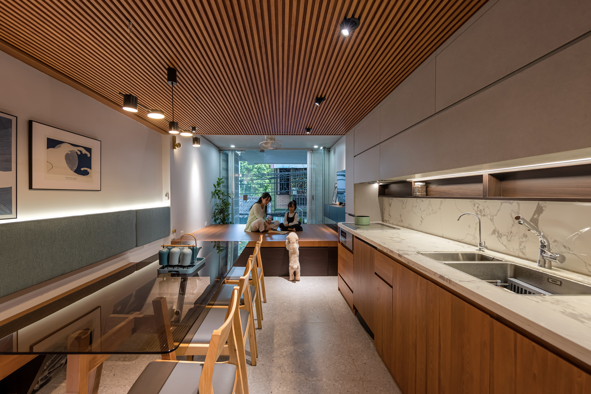 Open kitchen and dining space with timber slat ceiling, marble countertops, and two people seated at the table