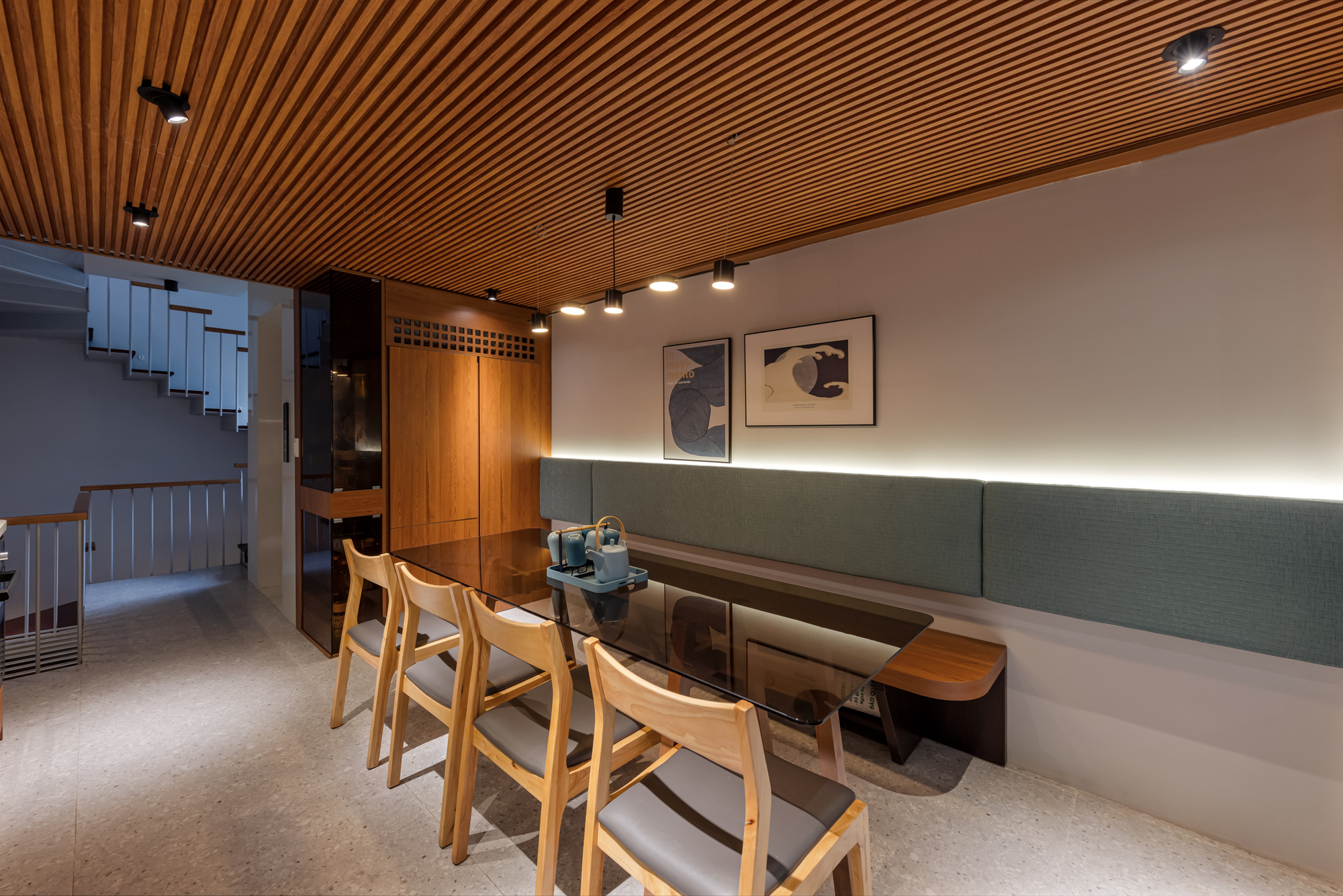 Built-in banquette seating with sage upholstery and timber table beneath a slatted timber ceiling
