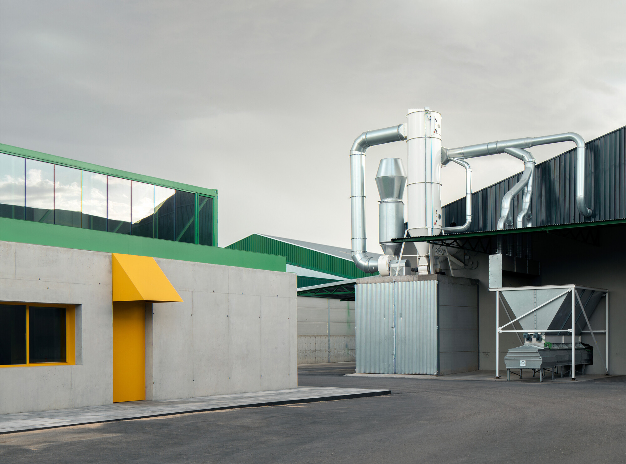 Industrial courtyard with yellow canopy entrance and exposed metal ventilation ducts overhead