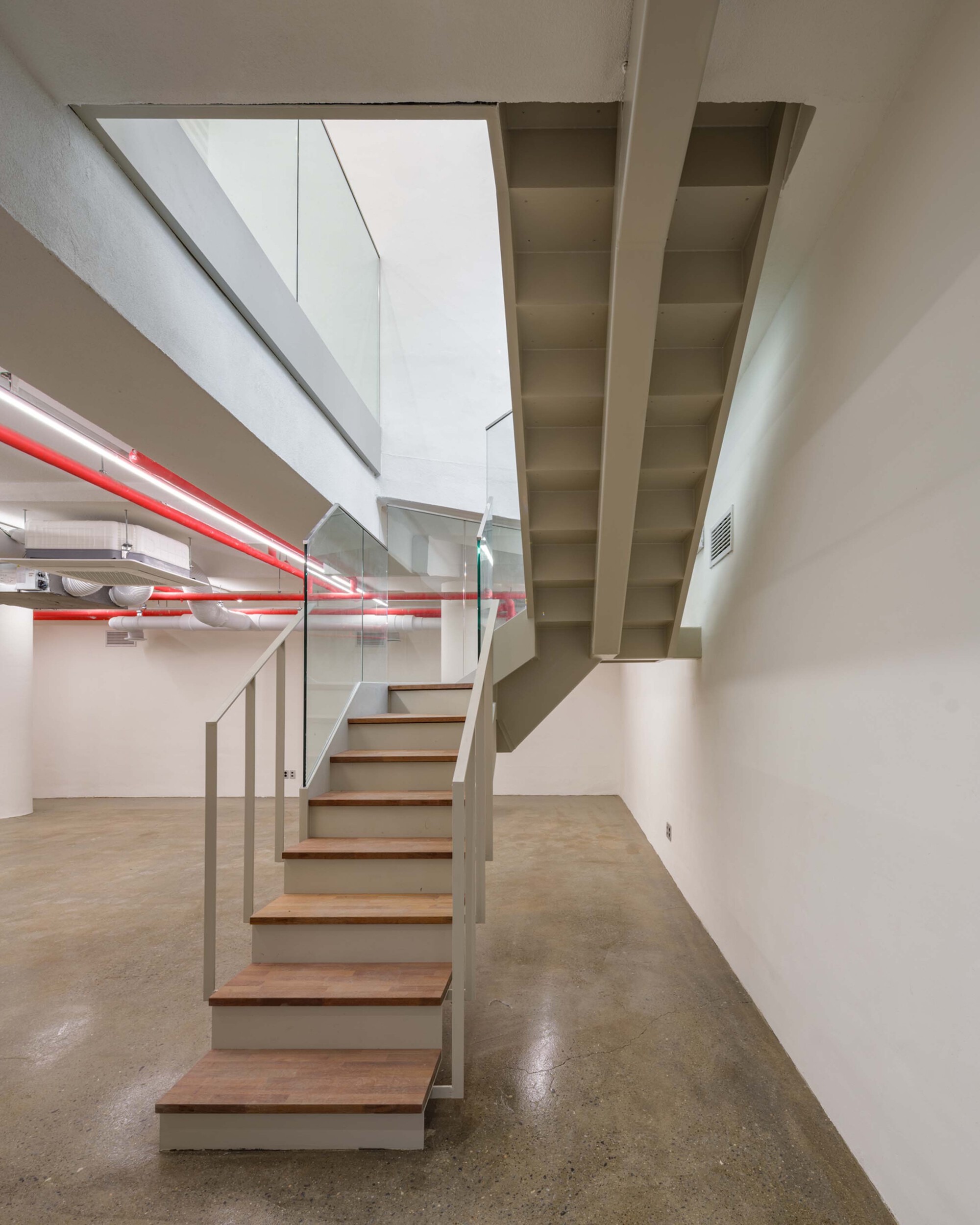 Open-tread staircase with timber treads and glass balustrade beneath a white coffered ceiling
