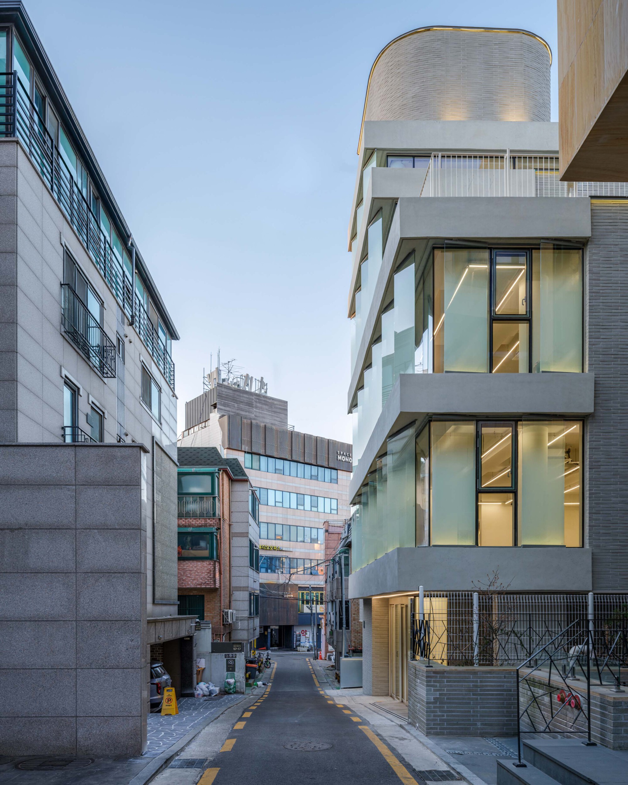 Narrow street view showing the curved brick tower between neighboring buildings at dusk