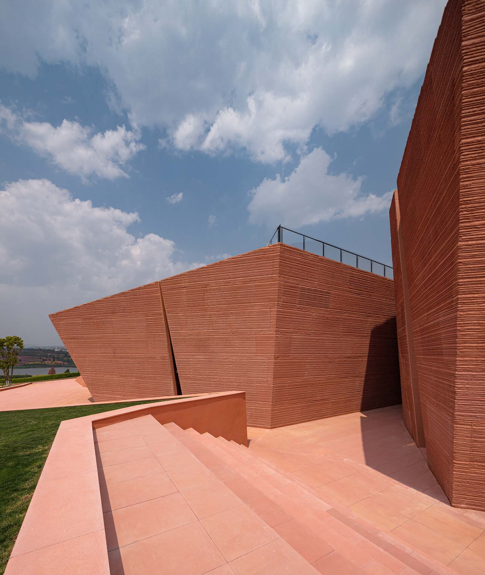 Rooftop terrace with salmon-colored paving and angled red brick walls under blue sky