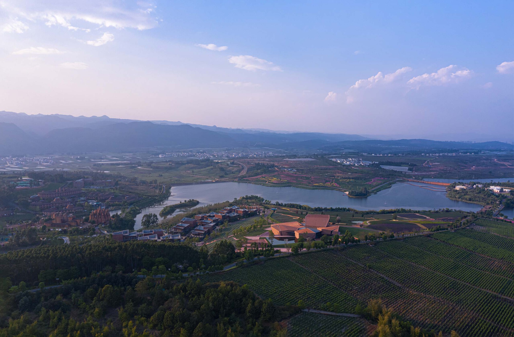 Distant aerial view of the complex nestled between lake and mountains at twilight