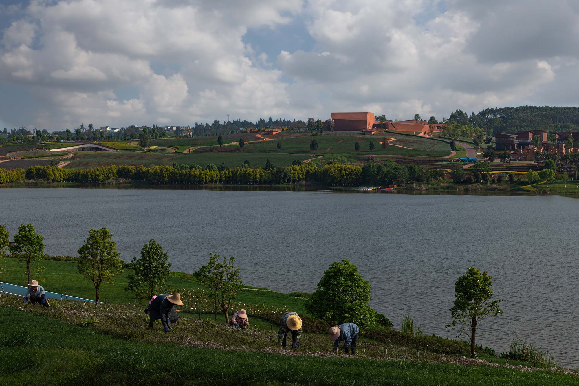 Distant view across the water of the compound on planted terraces under afternoon clouds