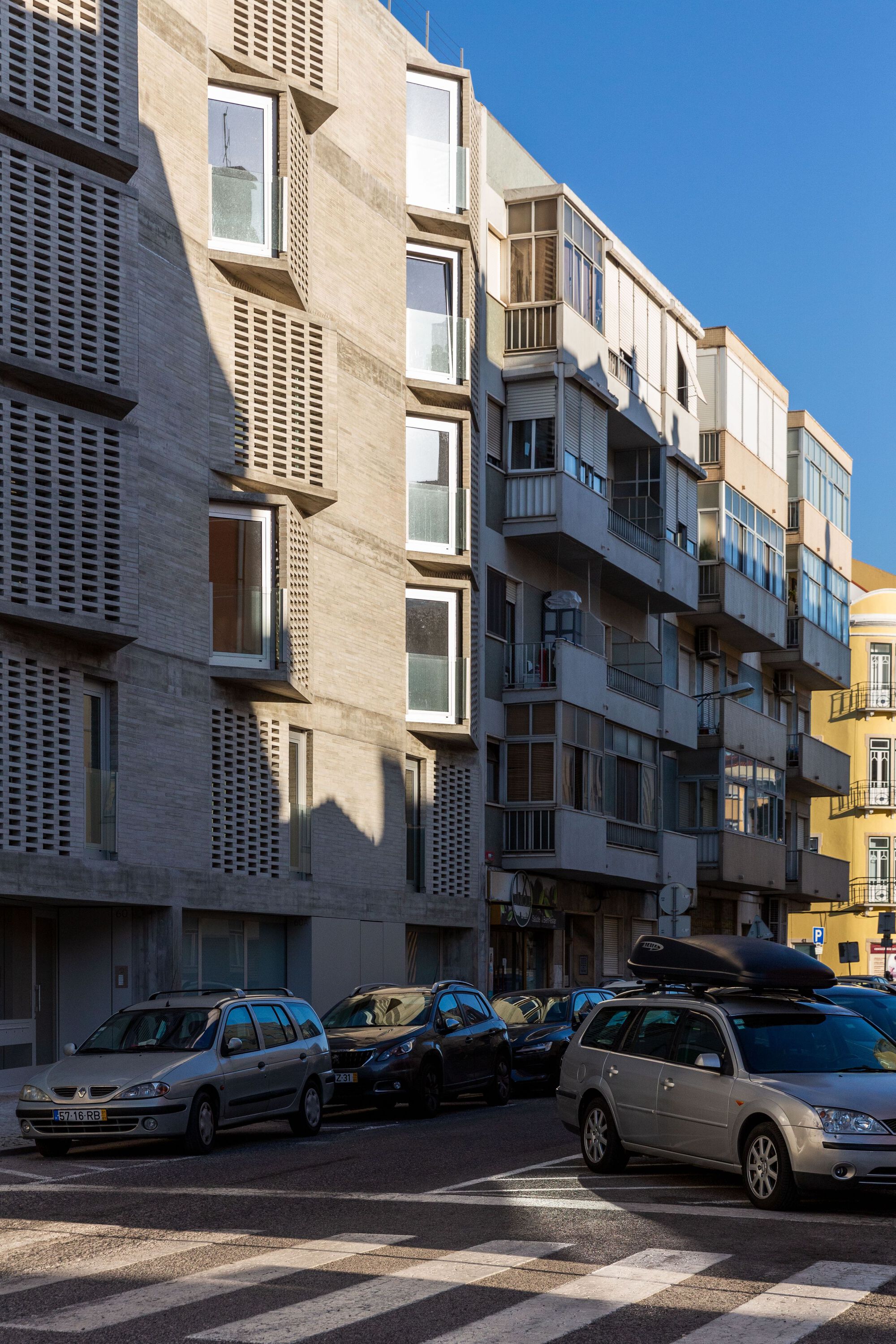 Low-angle view of the textured concrete facade with cantilevered balconies catching late afternoon sun