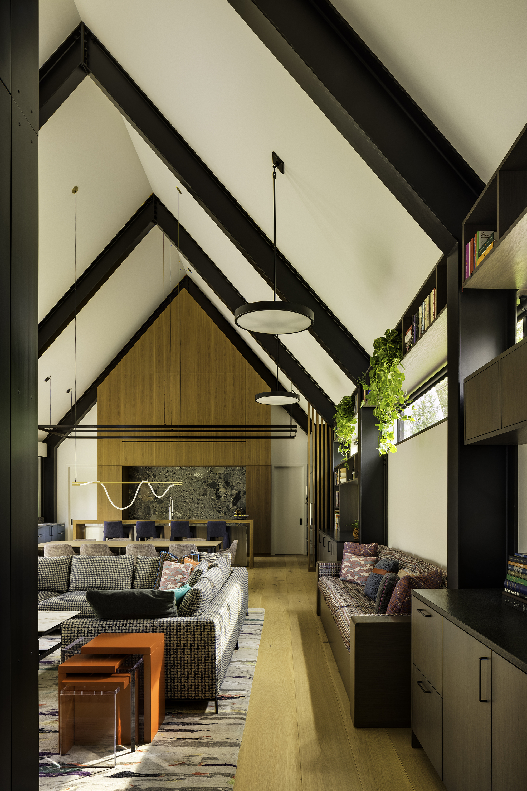 Double height living space with exposed black rafters and pendant lights above seating areas