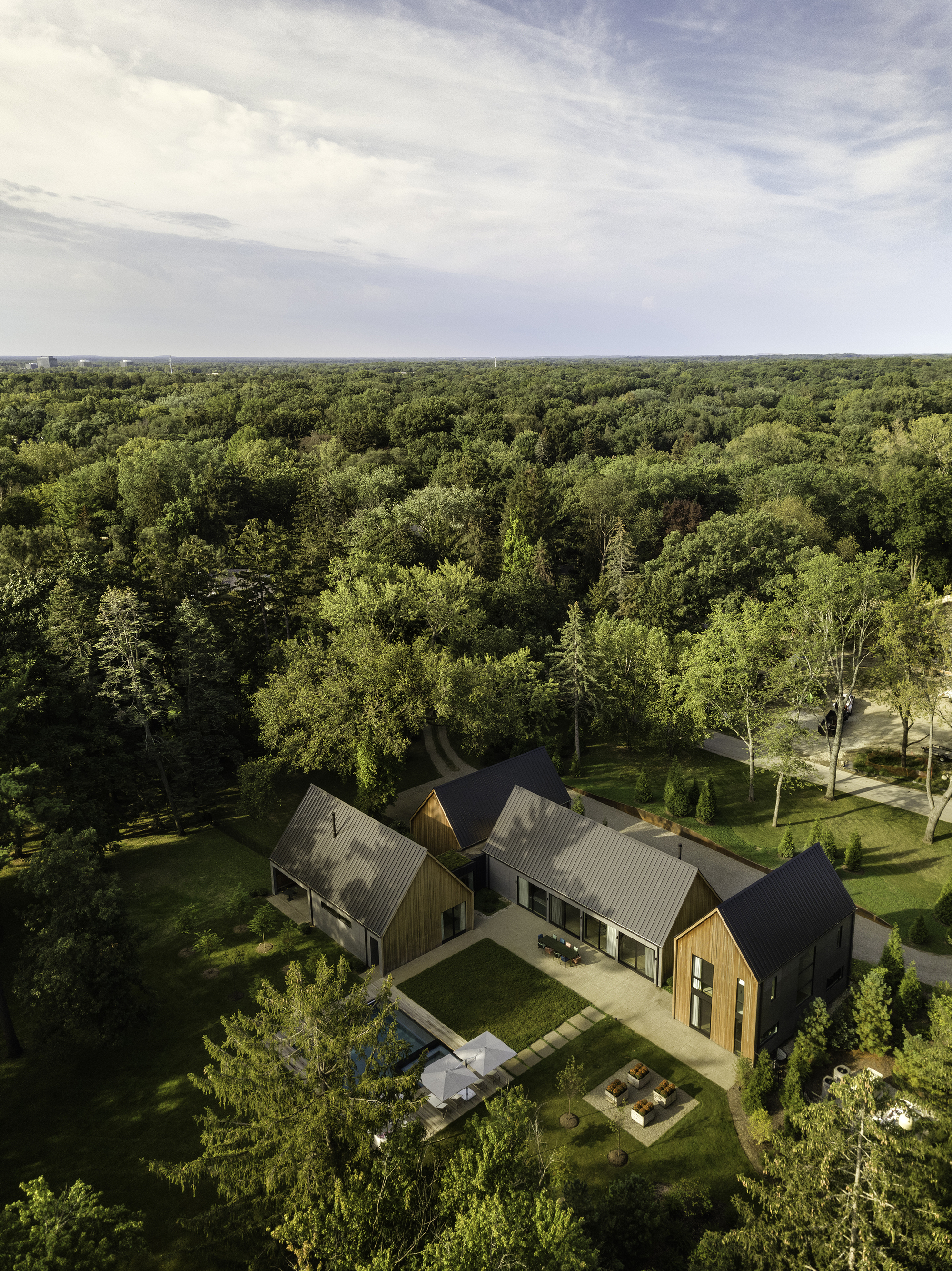 Drone view of the compound with rear terrace and lawn surrounded by dense forest