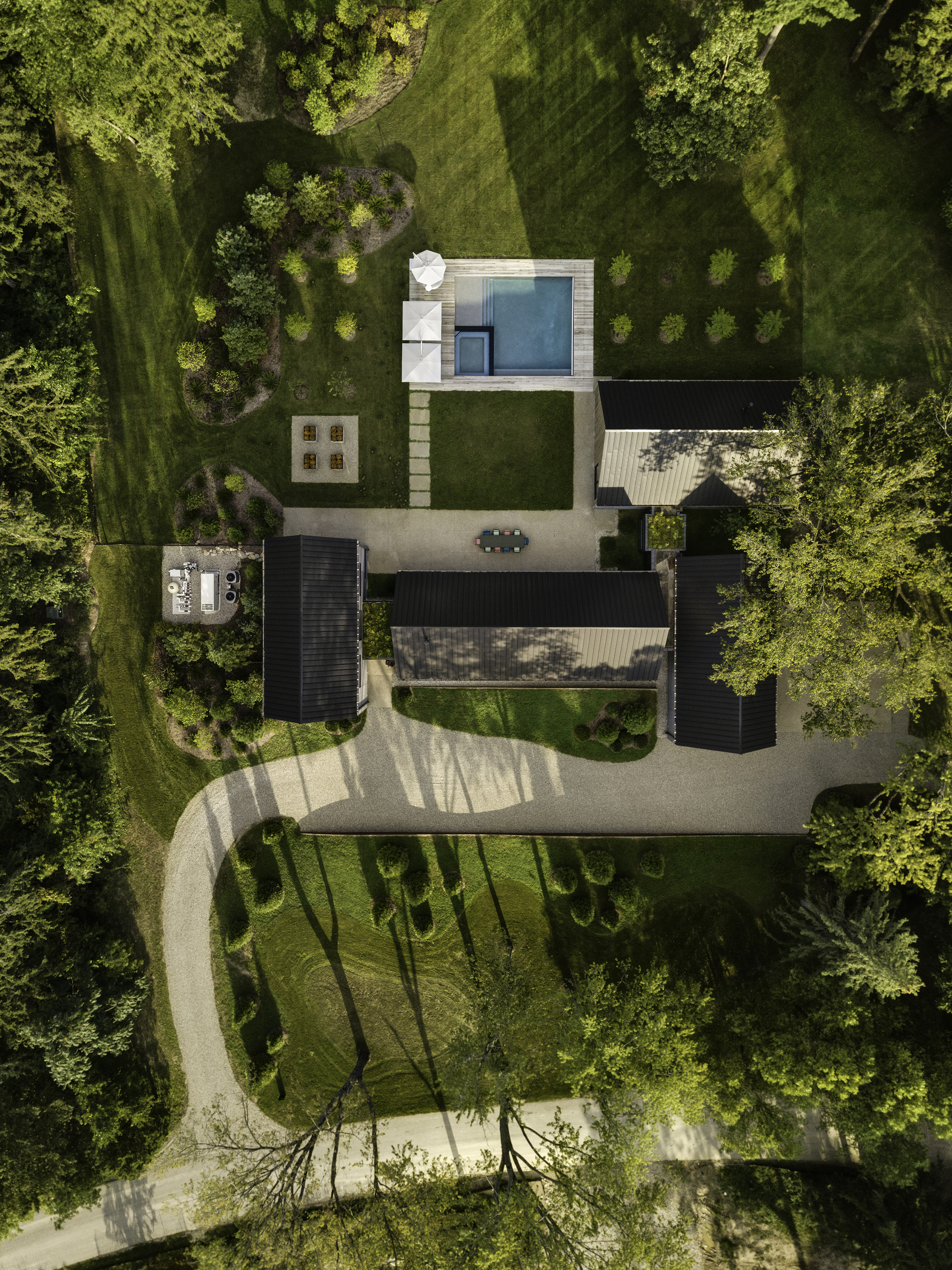 Top-down view showing curved gravel drive, courtyard spaces and scattered tree shadows on the ground