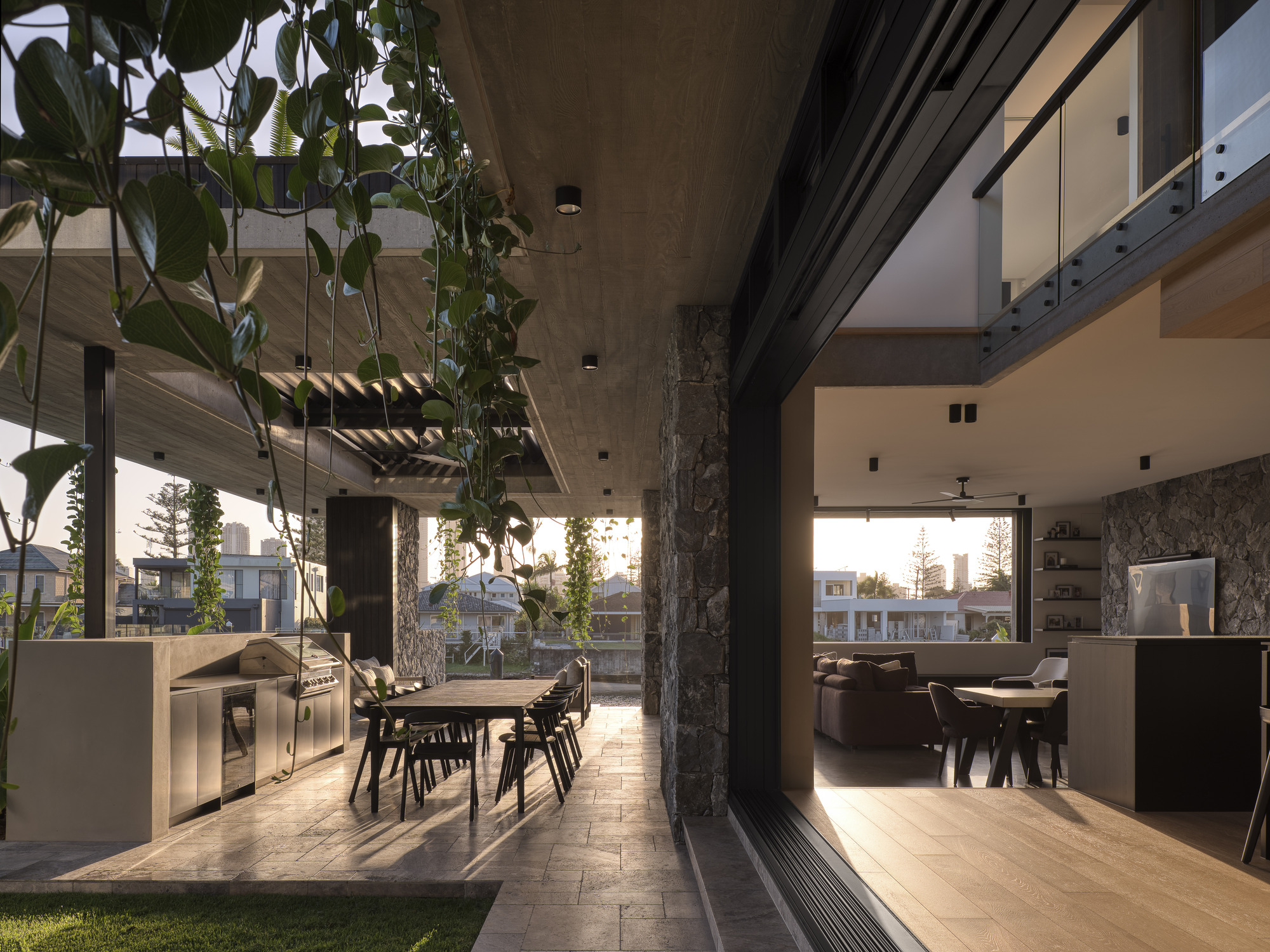Courtyard dining area with stone column, hanging plants and low afternoon sunlight streaming through