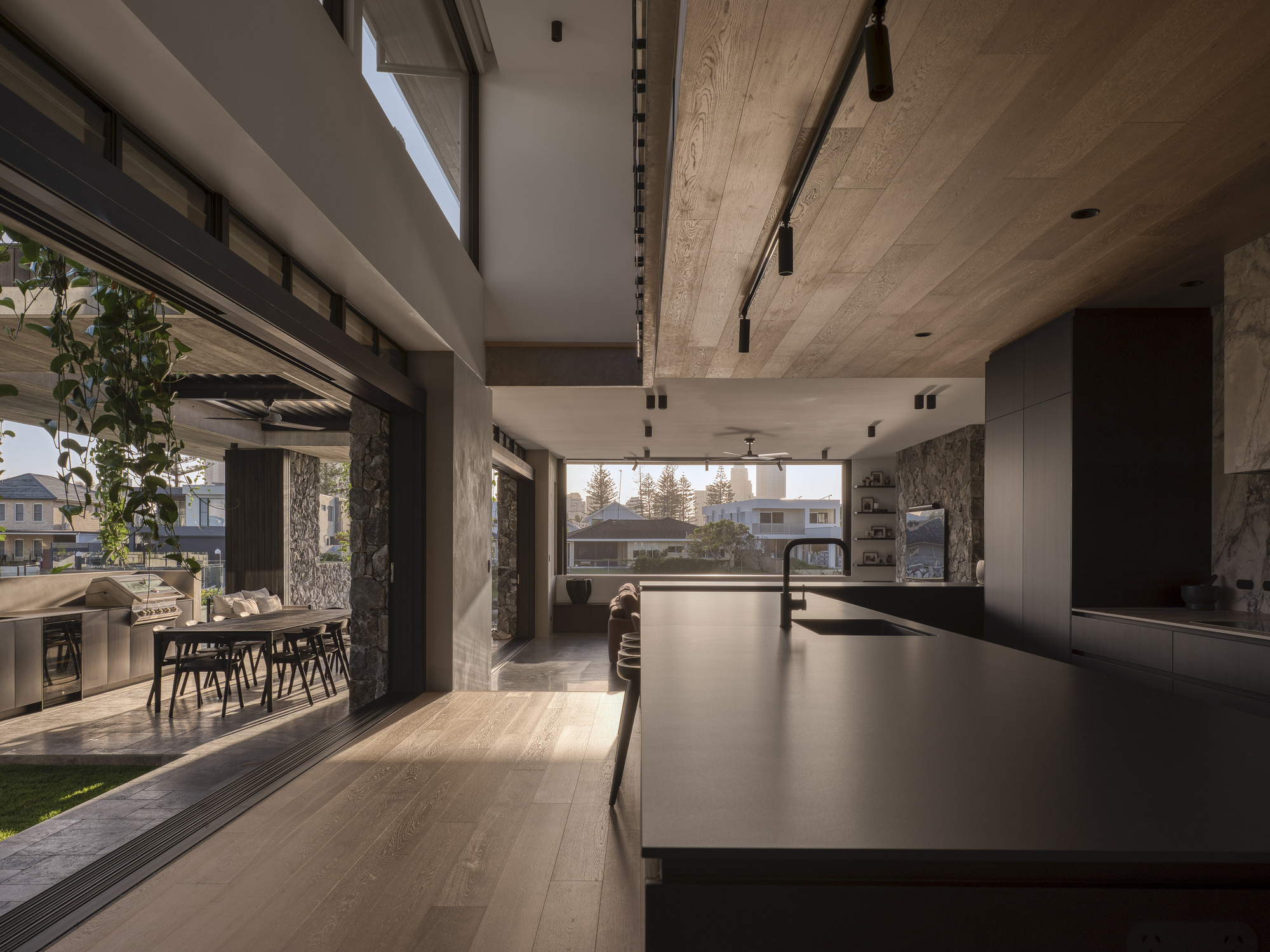 Kitchen island with view through multiple sliding glass doors to outdoor dining terrace at dusk