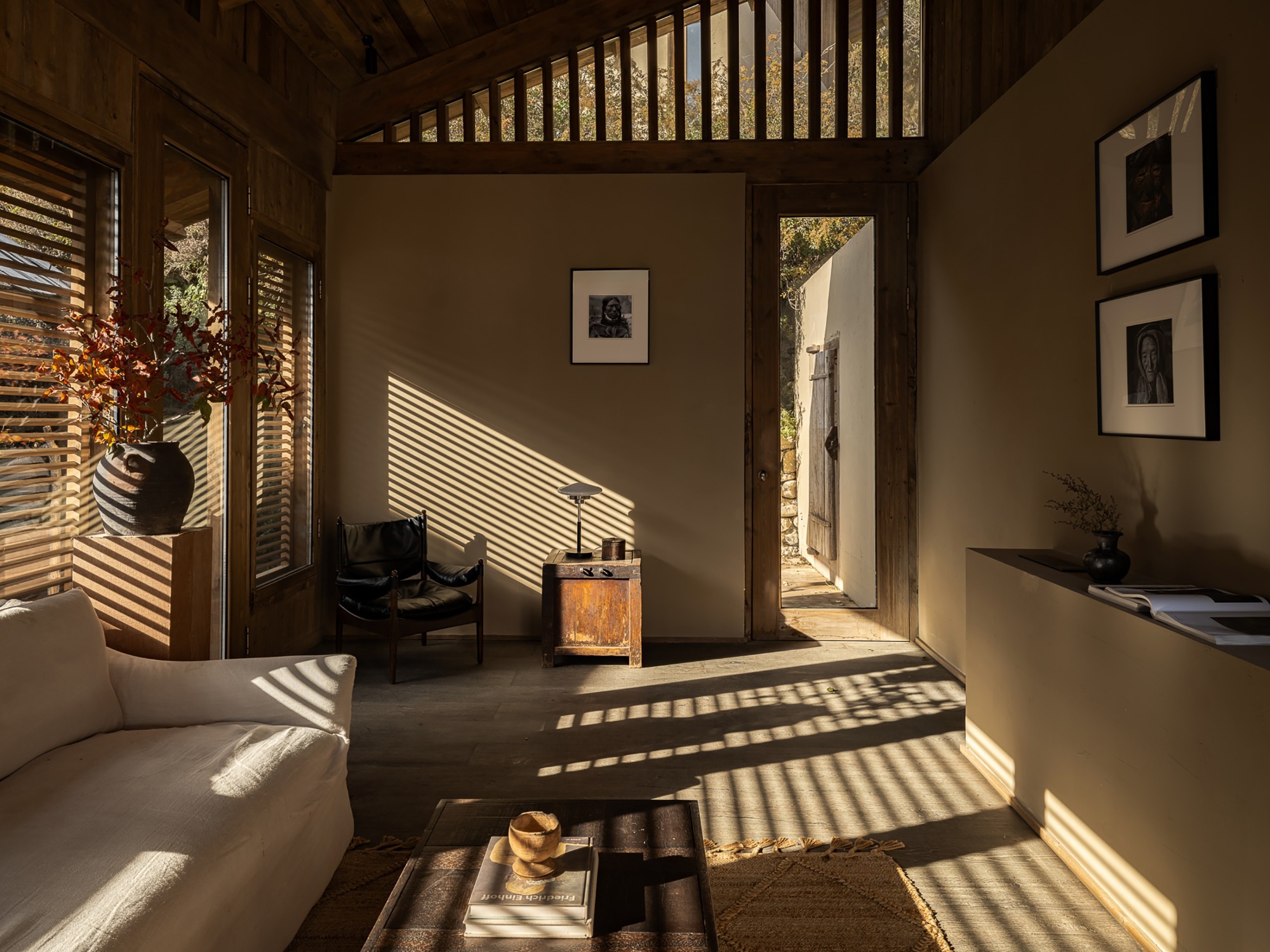 Living room with slatted wood shutters casting striped shadows across the floor in afternoon sunlight