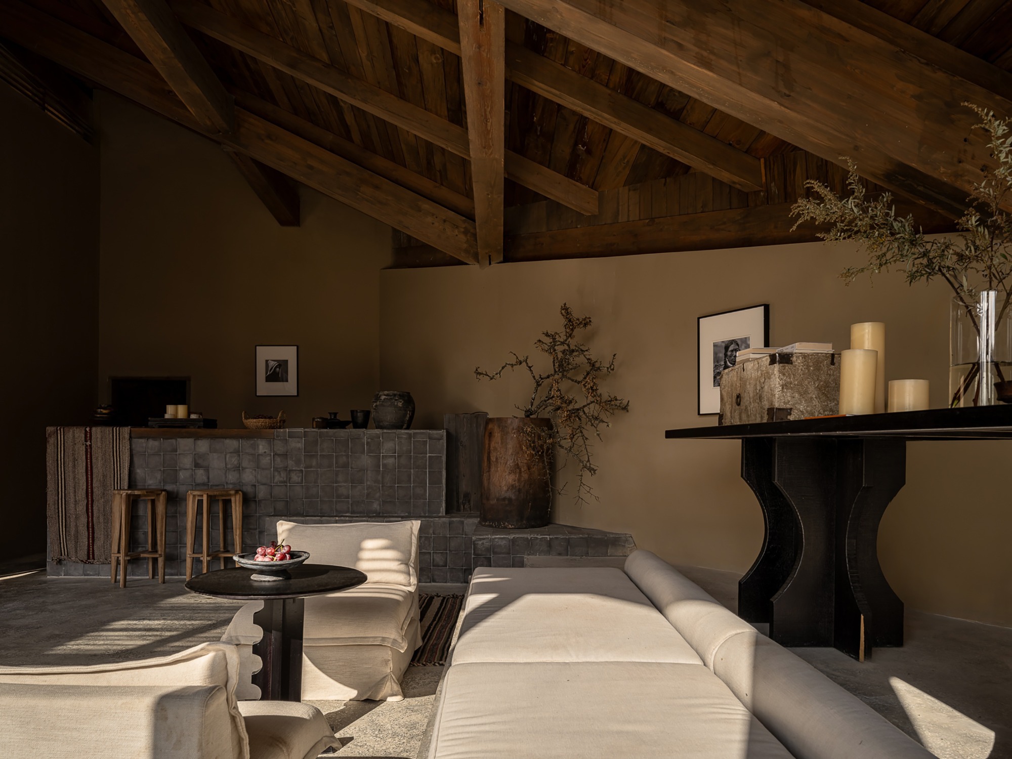 Living room with exposed timber ceiling beams and afternoon sunlight across furnishings