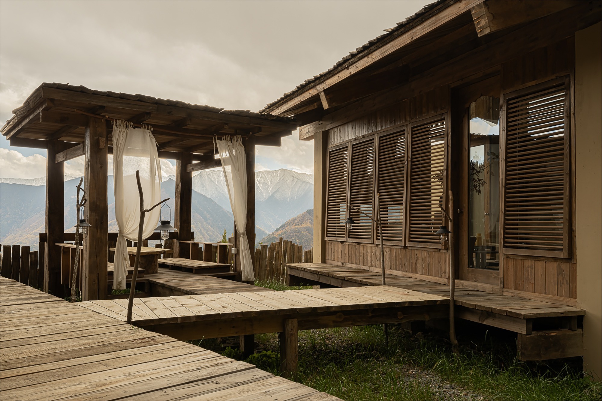 Raised timber deck with covered pavilion, louvered shutters and mountain range in the distance