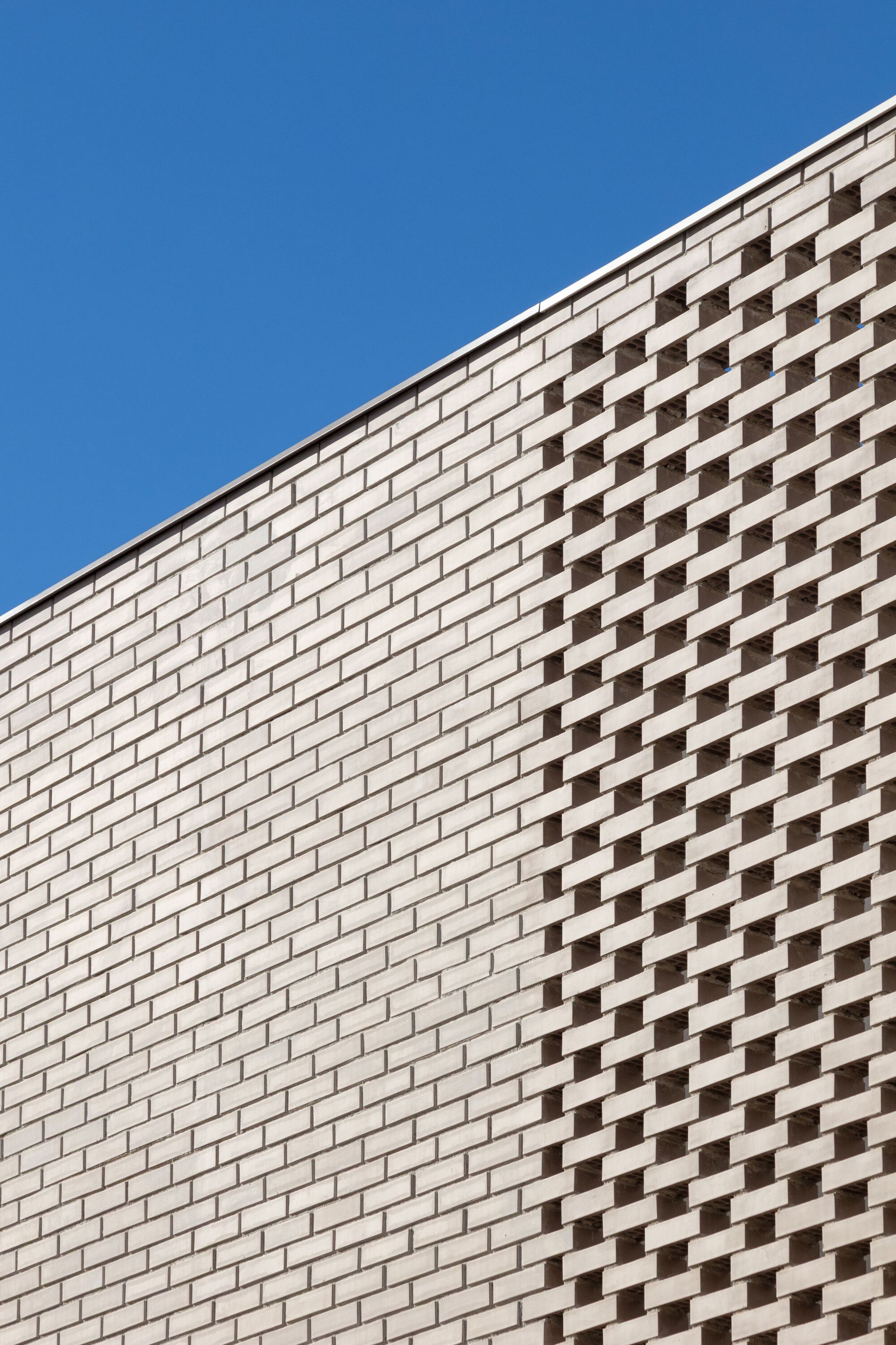 Close-up of buff brick wall with stepped checkerboard pattern against clear sky