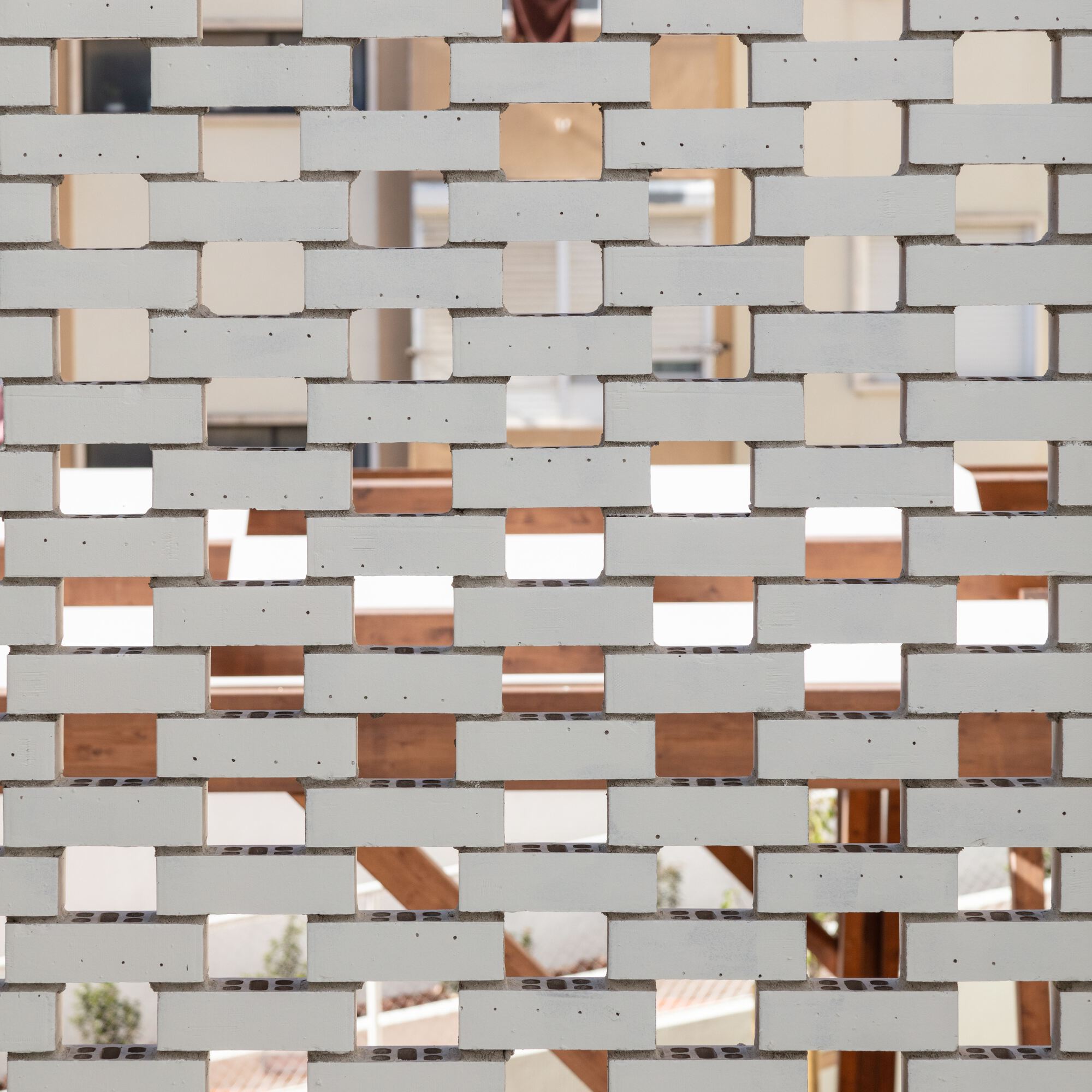 Perforated brick screen with mirrored glass infill creating a patterned translucent facade