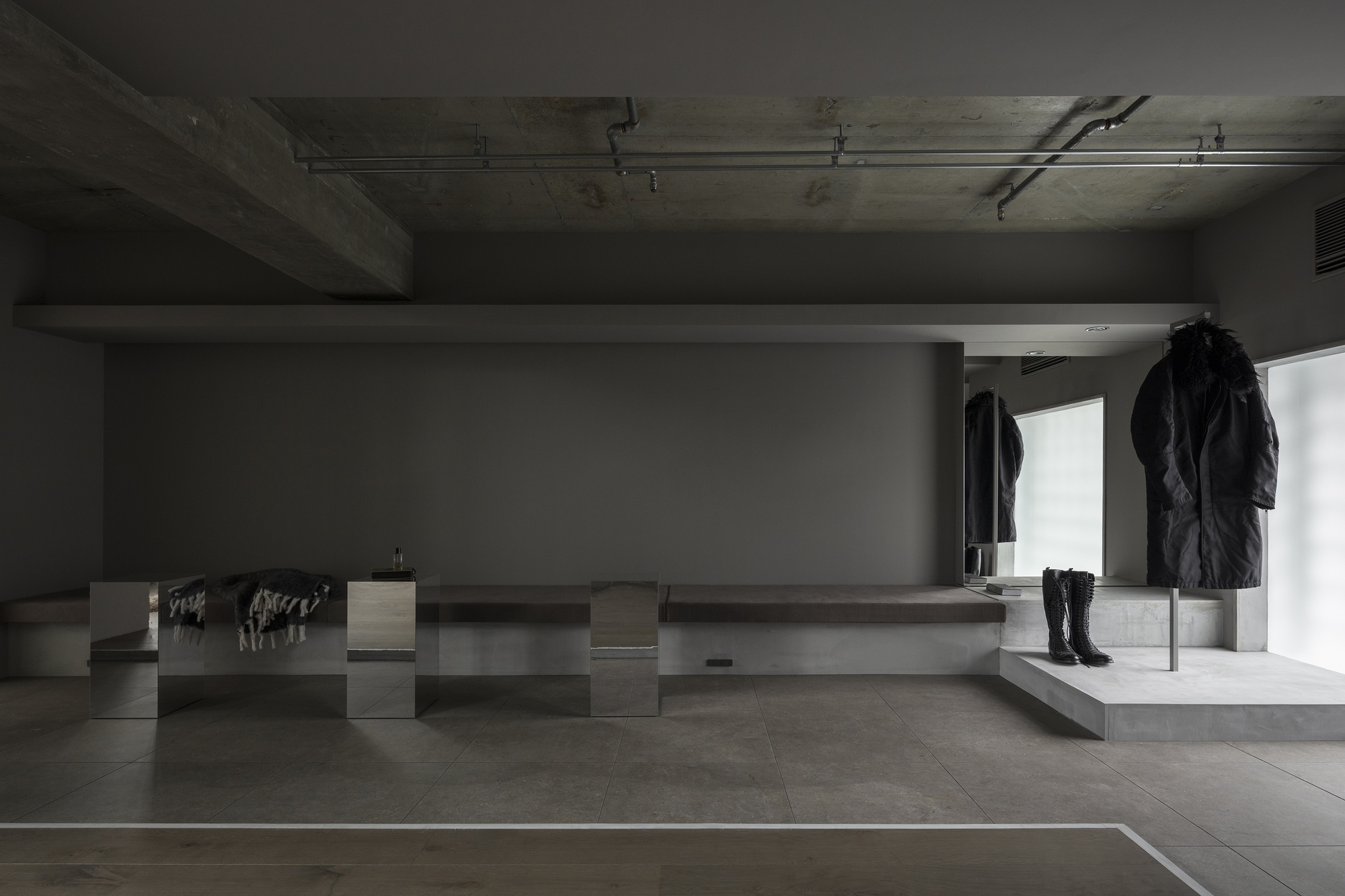 Retail display pedestals with garments beneath exposed concrete ceiling and recessed lighting