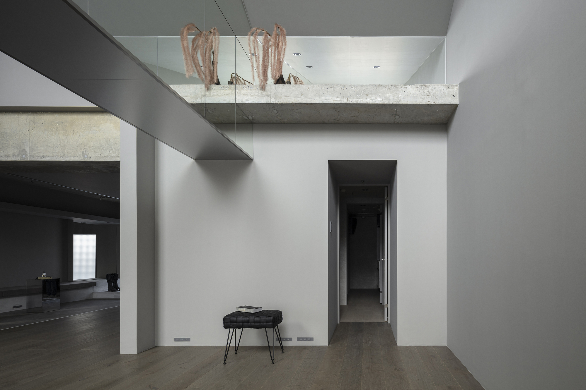 Double-height space with exposed concrete beam and mezzanine level above painted corridor
