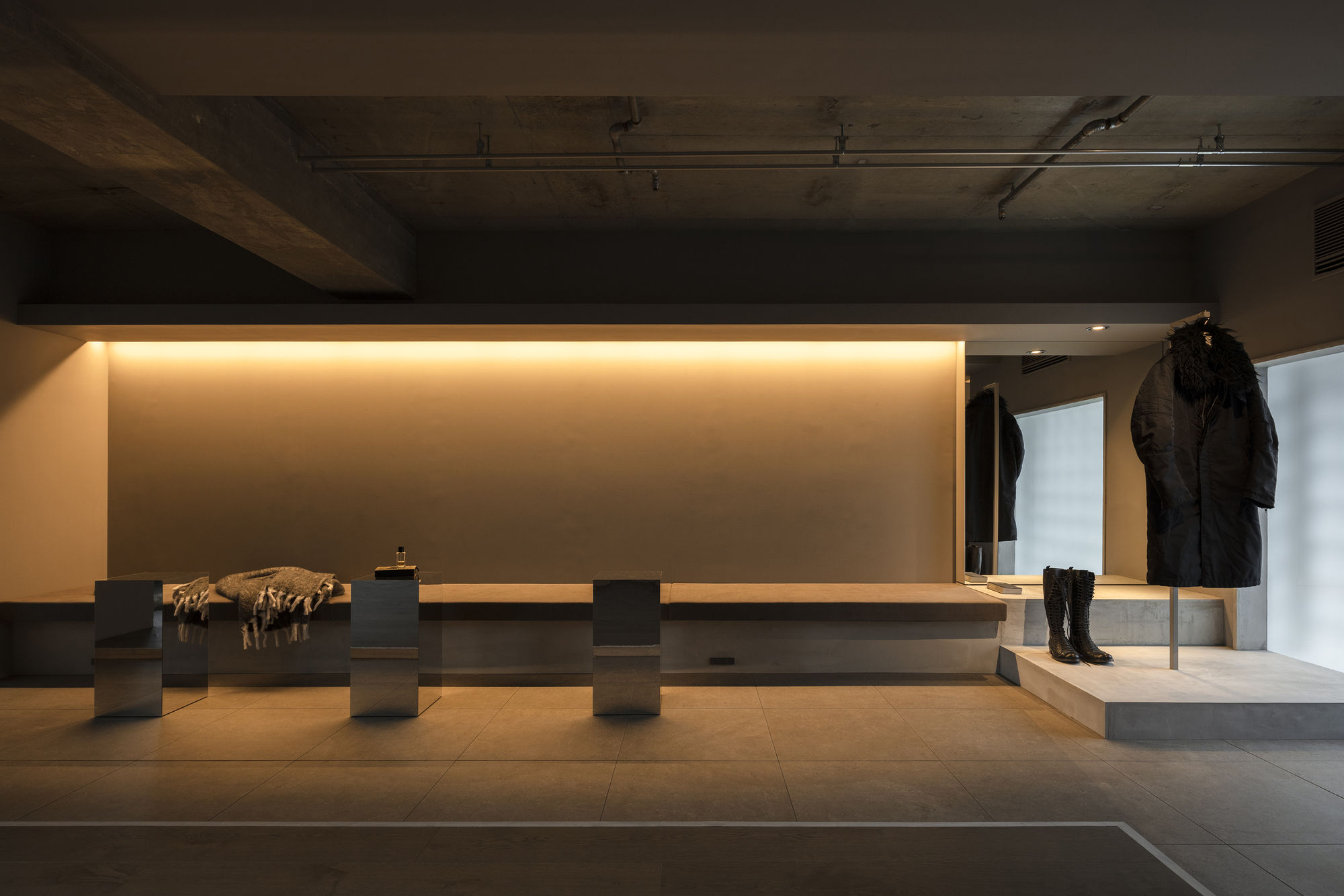 Lounge area with backlit timber bench seating and exposed concrete ceiling under warm lighting