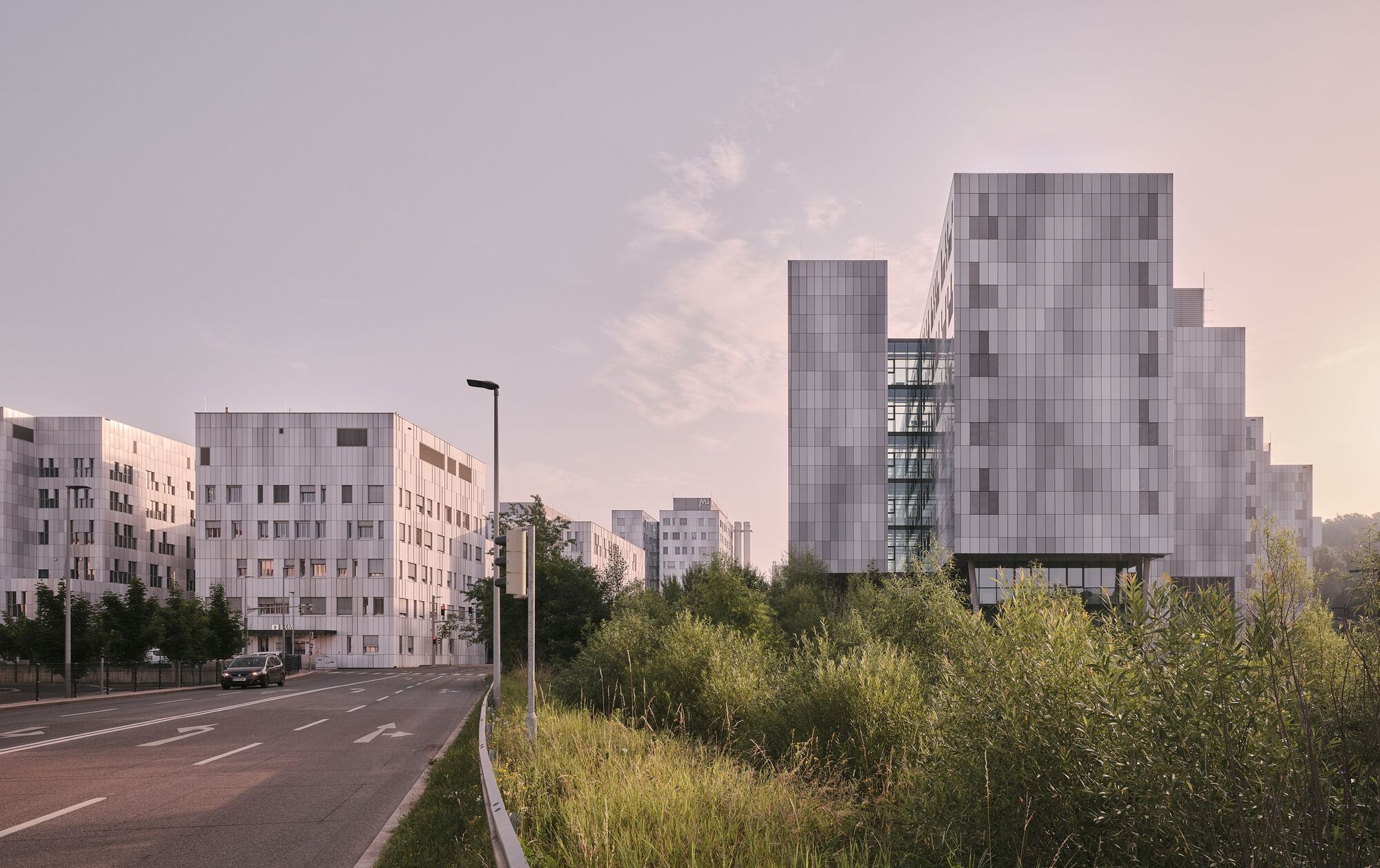 Cluster of panelized residential blocks adjacent to a roadway under a pink dusk sky