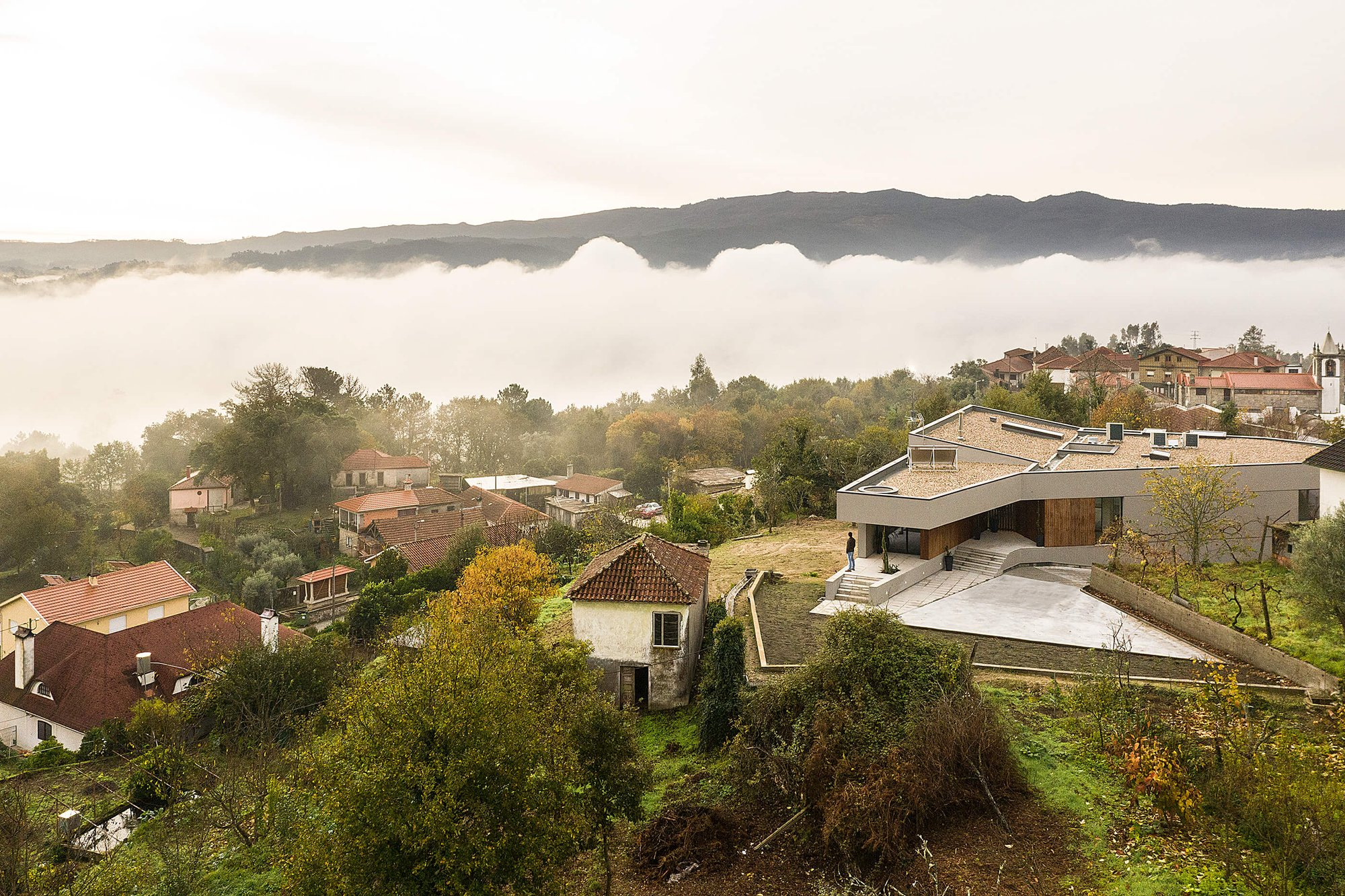 House positioned within a lush landscape, overlooking a misty valley context.