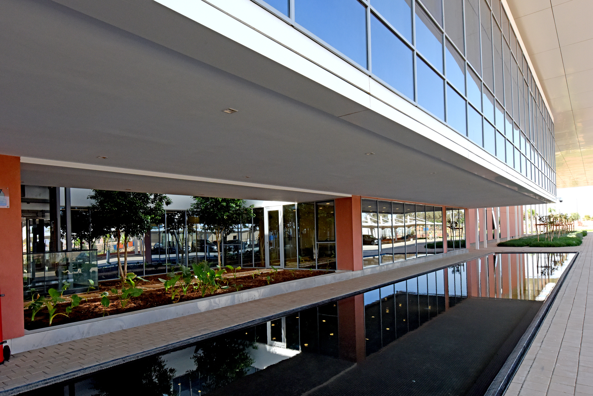 Reflecting pool mirroring the glazed upper level and planted courtyard beneath the cantilevered building volume
