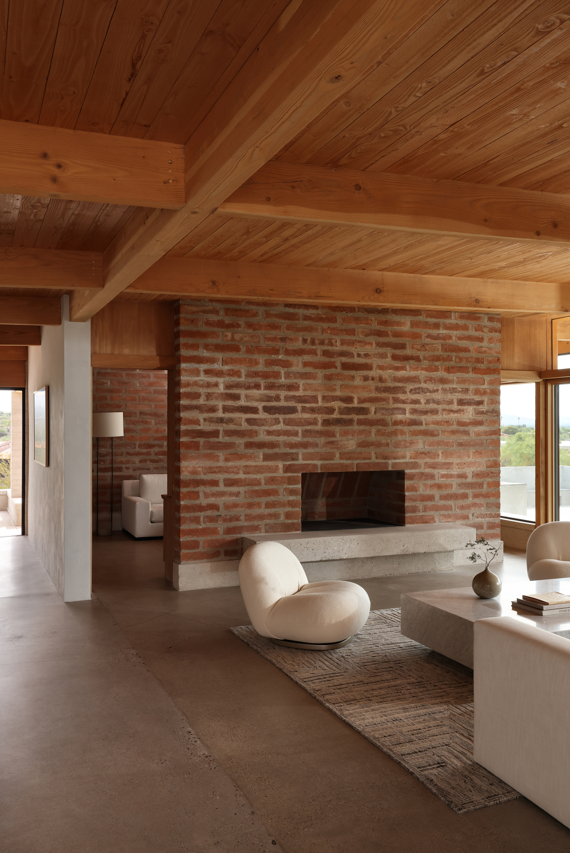 Brick fireplace wall meeting timber paneling under vaulted ceiling with diagonal wood planking