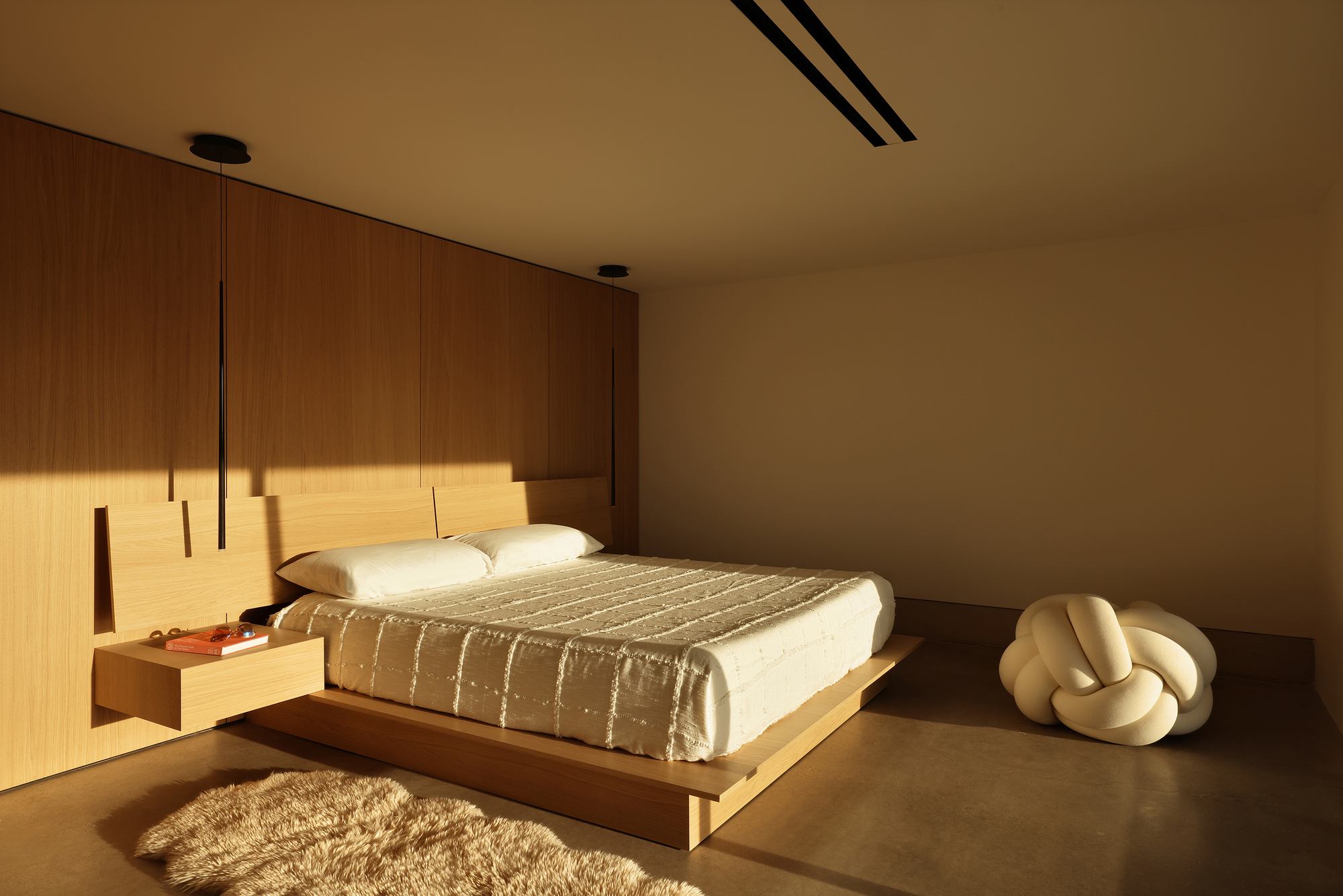 Bedroom with platform bed and timber wall panels in warm afternoon light