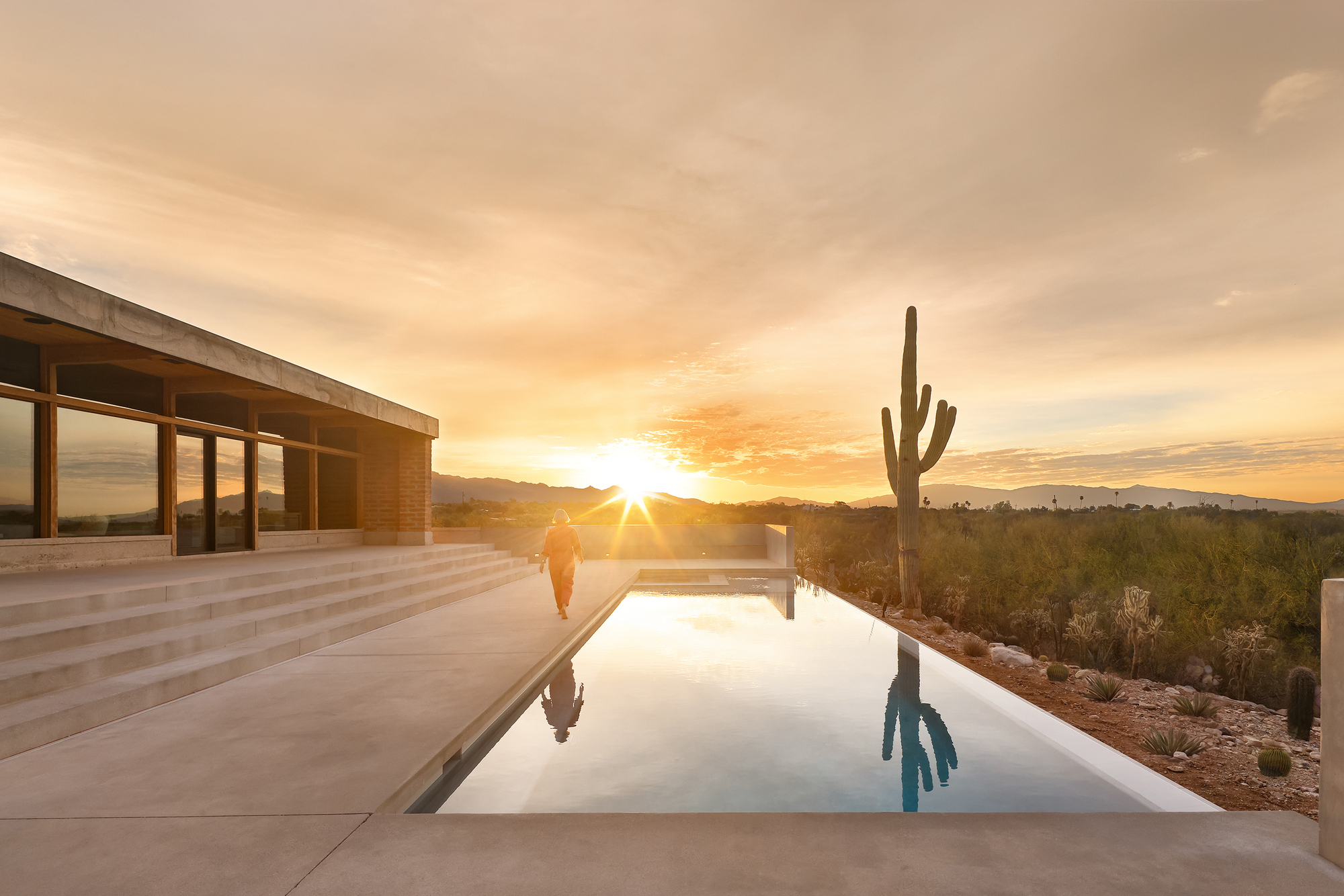Reflecting pool with concrete deck and saguaro cactus at sunset in the desert landscape