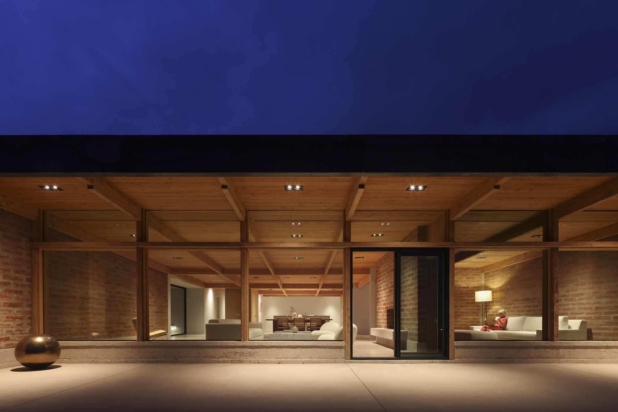 Coffered timber ceiling and full-height glazing framing the interior living spaces at night