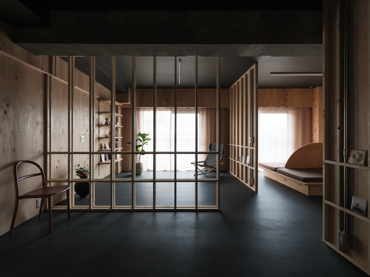 Open living space with timber-framed glass partitions dividing zones under a black ceiling